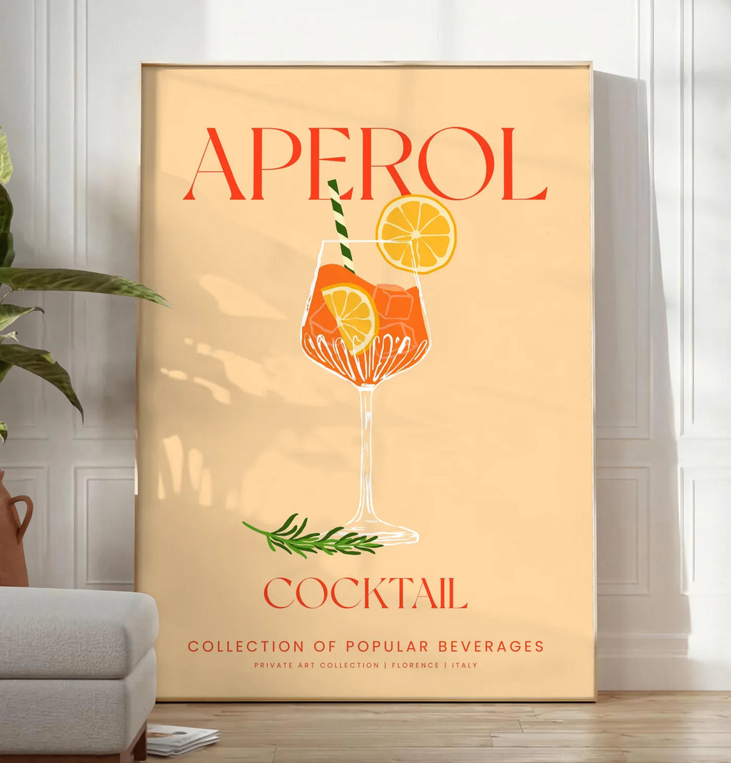 Reproduction affiche cocktail Aperol Spritz, posee au sol dans un salon minimaliste clair, a cote d'un canape beige et d'une plante verte, sur un parquet clair