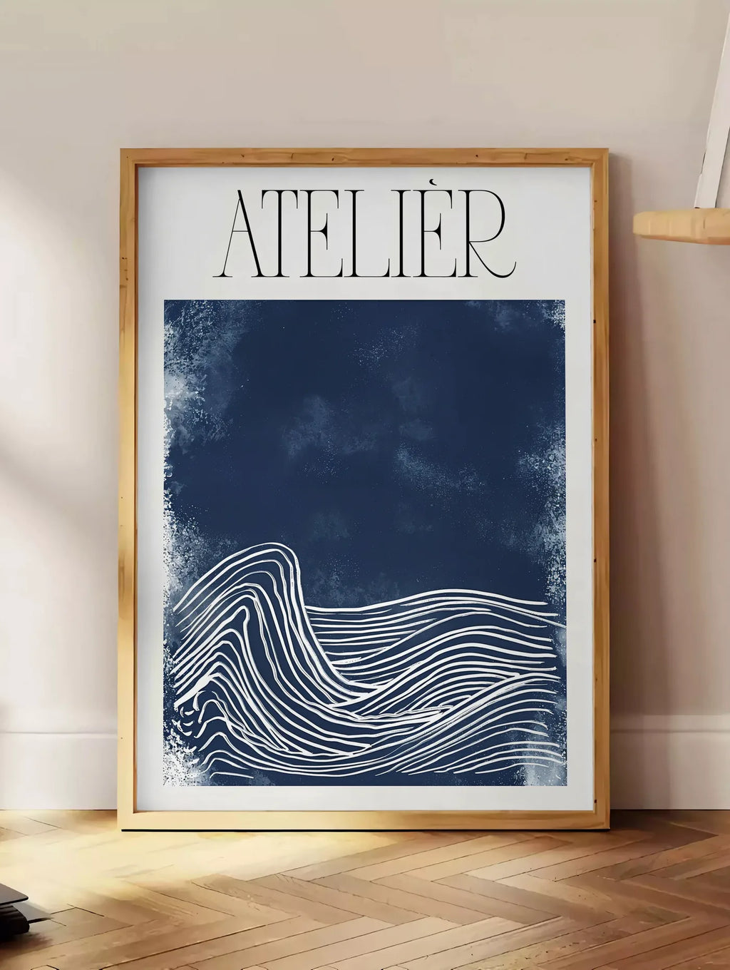 Estampe affiche Atelier vagues minimaliste, posee au sol dans un coin salon, sur un parquet a chevrons, pres d'une table d'appoint en chene chargee de livres