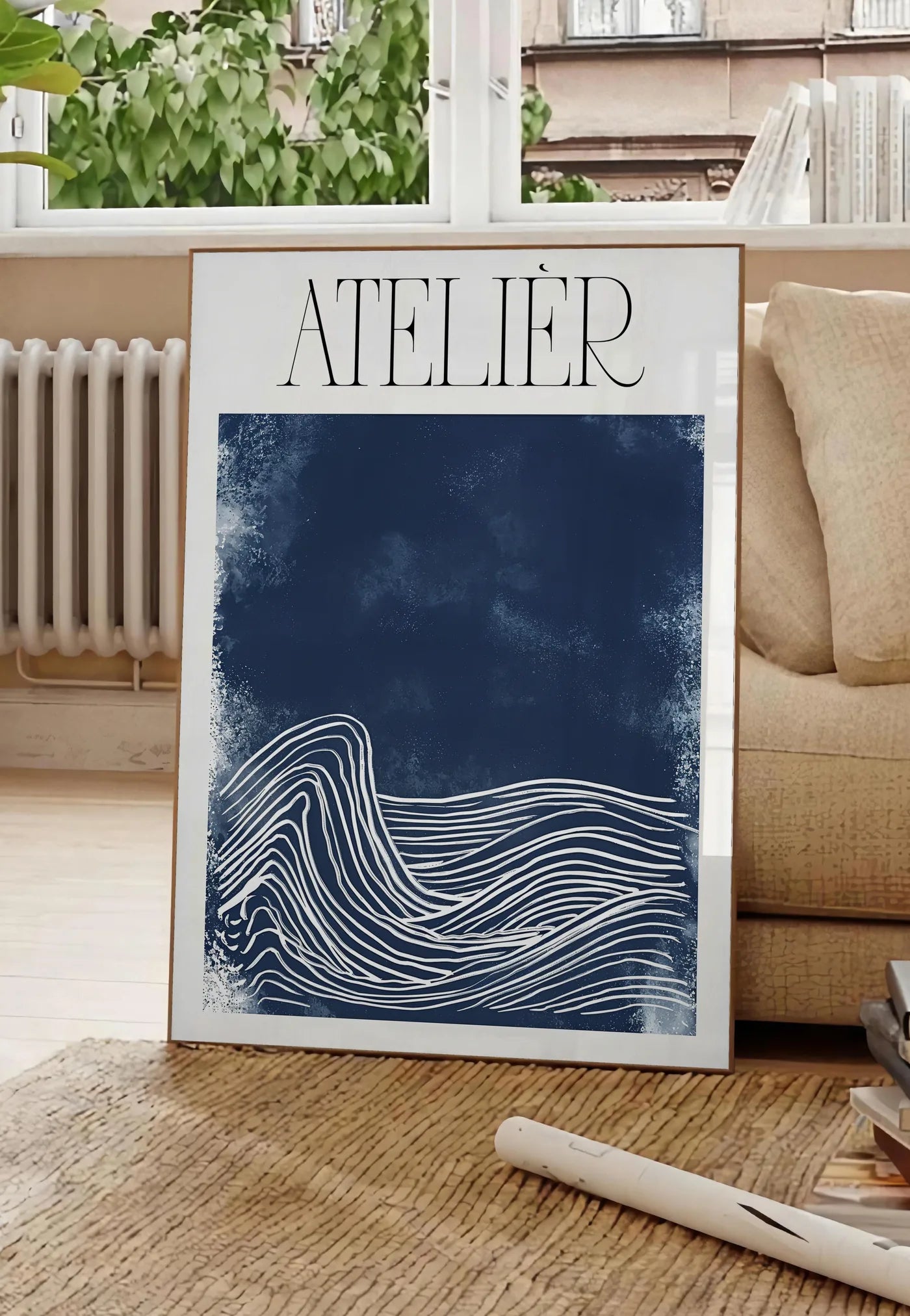 Poster affiche Atelier vagues minimaliste, posee au sol dans un salon parisien, devant une grande fenetre donnant sur un immeuble haussmannien, entre un ficus et un canape creme