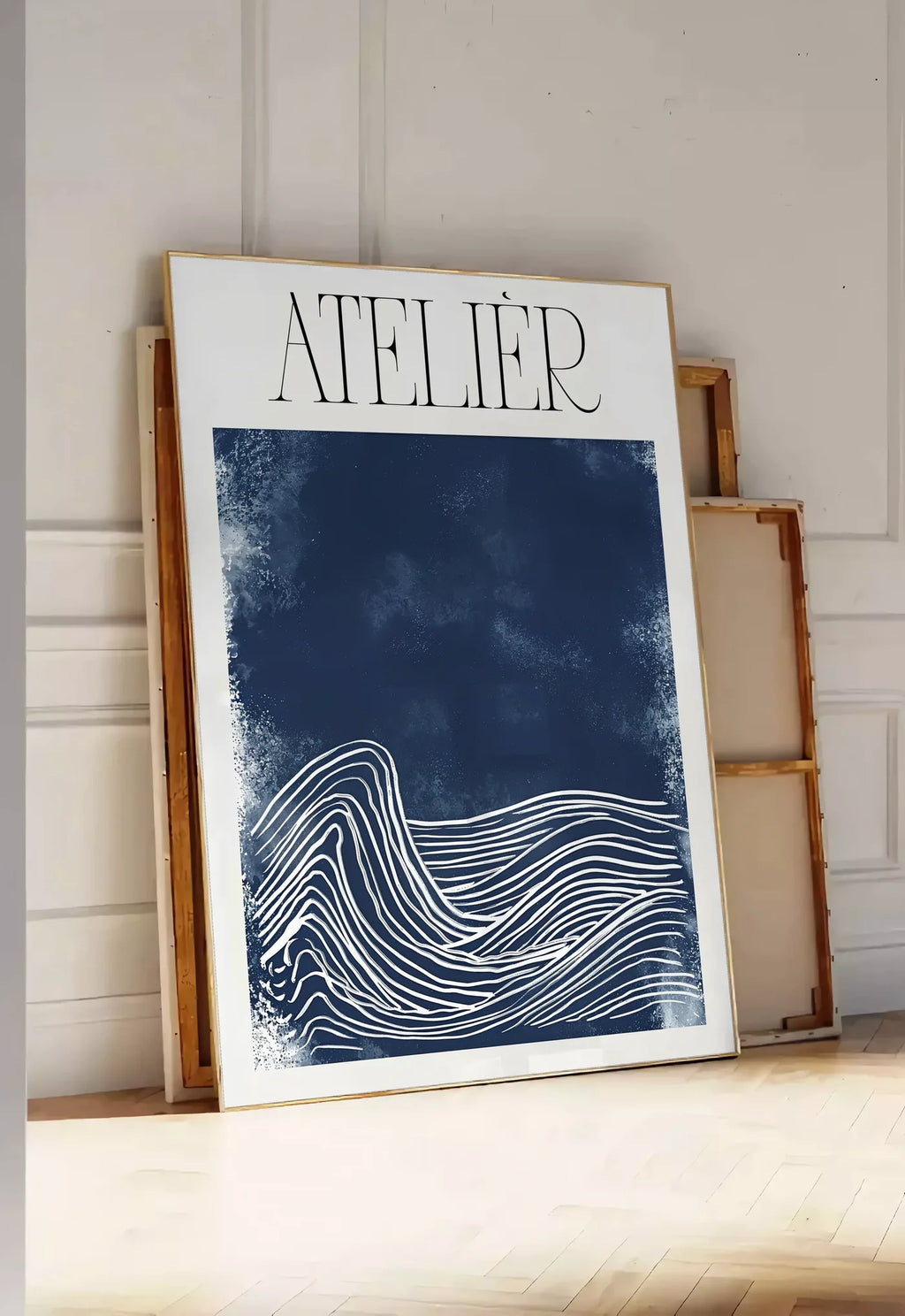 Tirage encadrable affiche Atelier vagues minimaliste, posee au sol dans une entree lumineuse, contre un mur a panneaux blancs, a cote de chassis en bois empiles