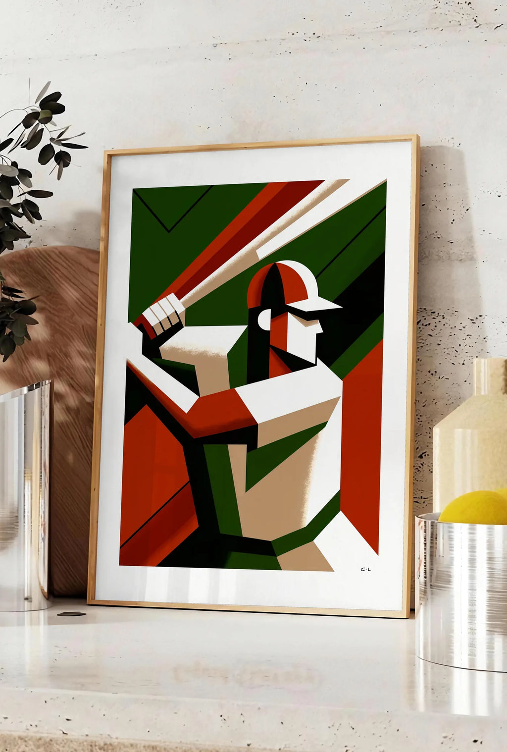 Affiche joueur de baseball en position de frappe, posee sur un plan de travail de cuisine en pierre claire, entre une branche d'eucalyptus en vase et un bocal de citrons