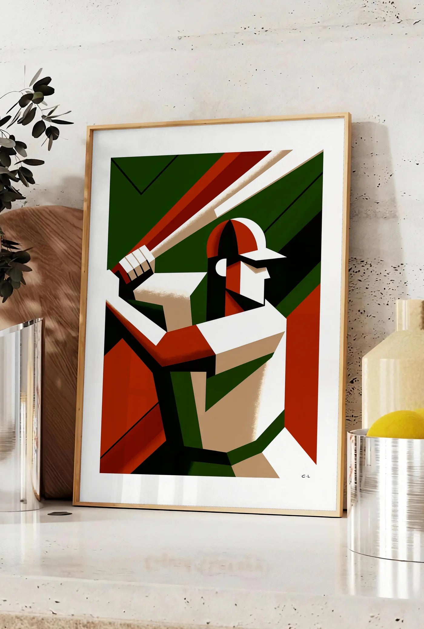 Affiche joueur de baseball en position de frappe, posee sur un plan de travail de cuisine en pierre claire, entre une branche d'eucalyptus en vase et un bocal de citrons