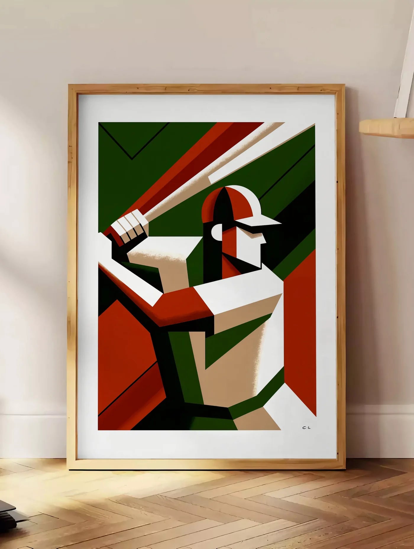 Estampe joueur de baseball en position de frappe, posee au sol dans un coin salon, sur un parquet a chevrons, pres d'une table d'appoint en chene chargee de livres