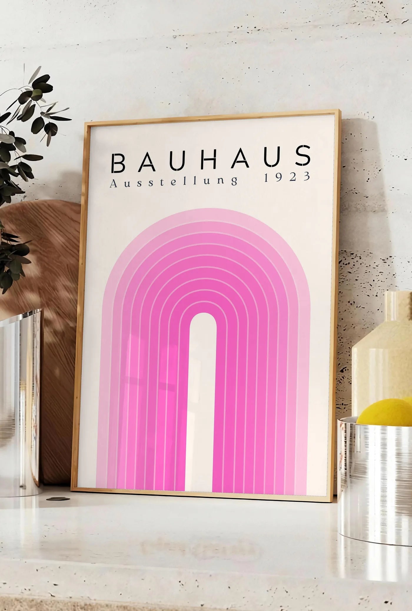 Affiche arche Rose, posee sur un plan de travail de cuisine en pierre claire, entre une branche d'eucalyptus en vase et un bocal de citrons