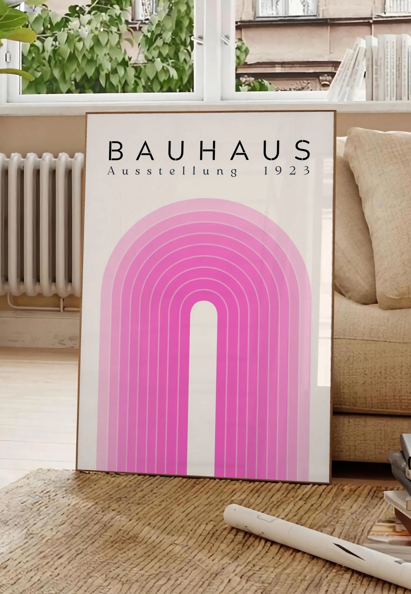 Poster arche Rose, posee au sol dans un salon parisien, devant une grande fenetre donnant sur un immeuble haussmannien, entre un ficus et un canape creme