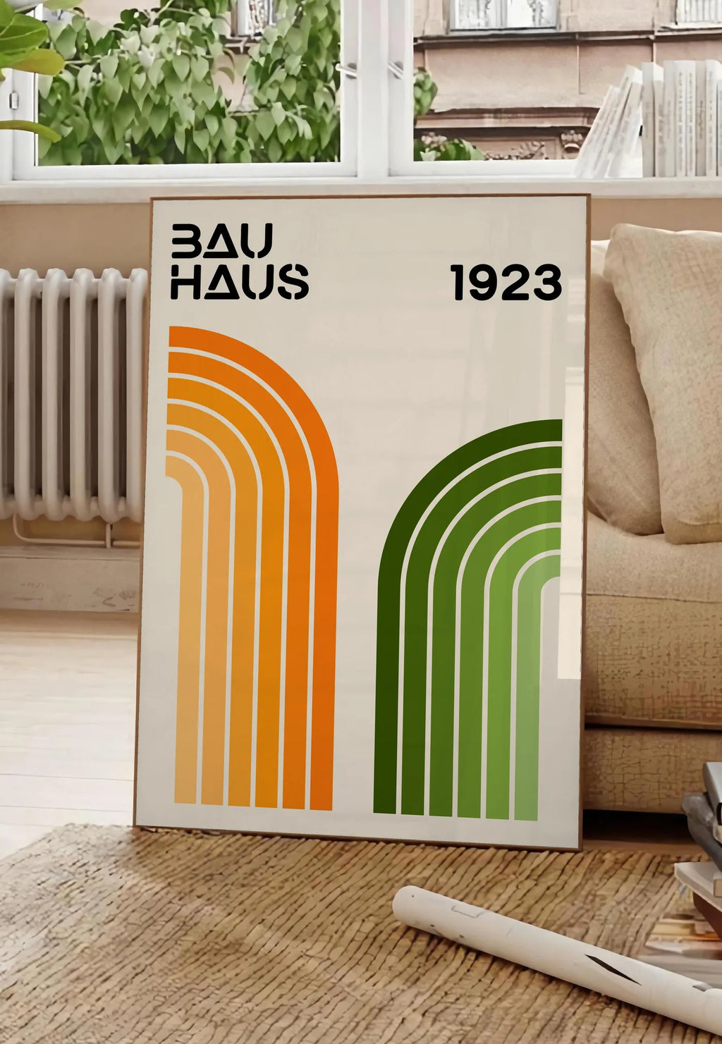 Poster arches Orange et Vert, posee au sol dans un salon parisien, devant une grande fenetre donnant sur un immeuble haussmannien, entre un ficus et un canape creme