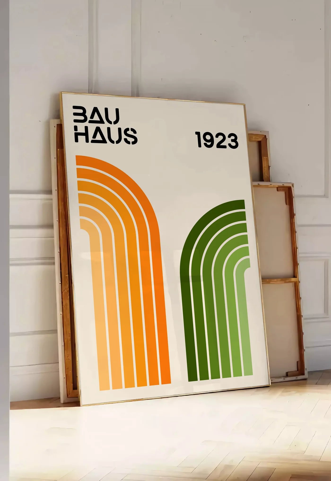 Tirage encadrable arches Orange et Vert, posee au sol dans une entree lumineuse, contre un mur a panneaux blancs, a cote de chassis en bois empiles