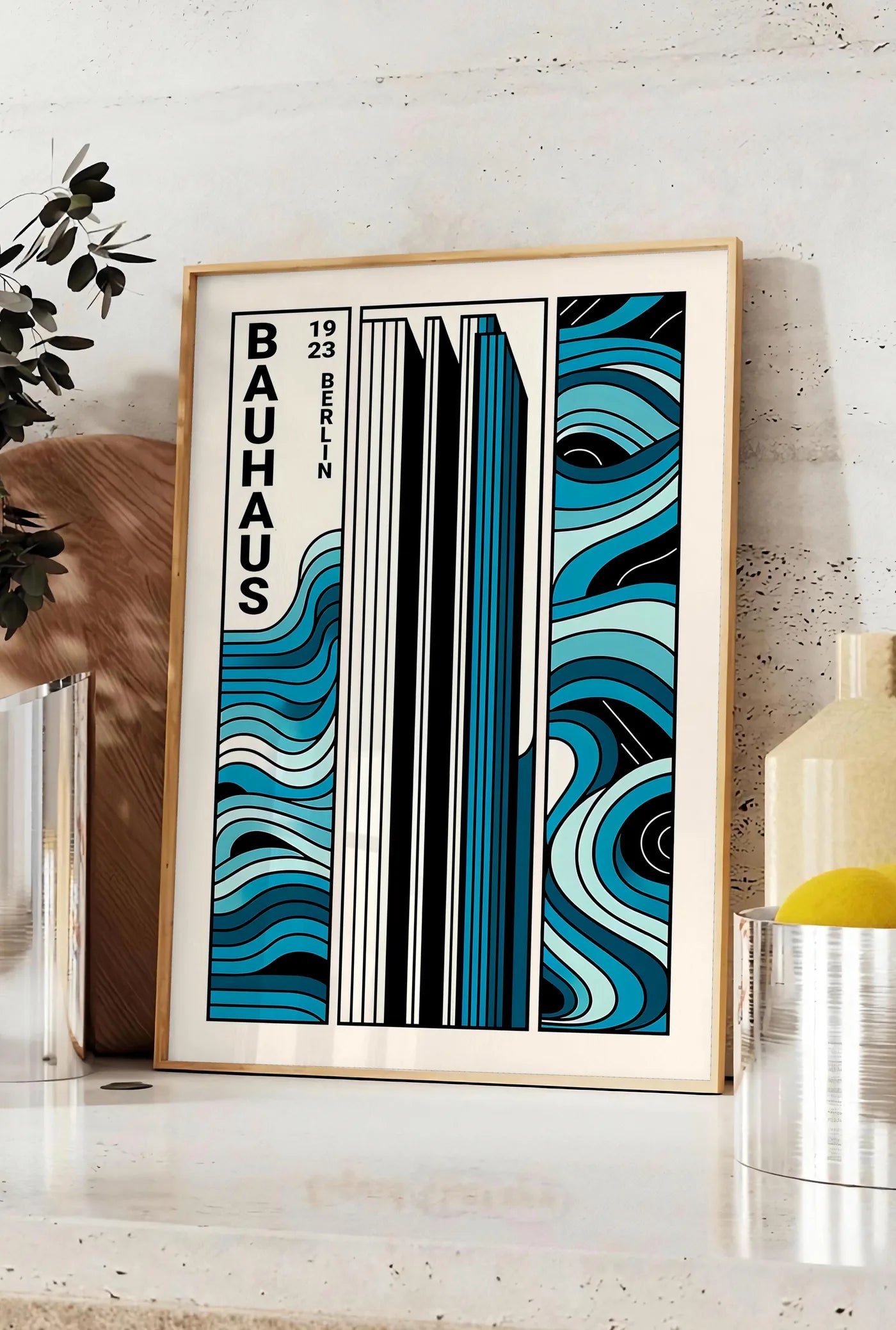 Affiche berlin Triptyque, posee sur un plan de travail de cuisine en pierre claire, entre une branche d'eucalyptus en vase et un bocal de citrons