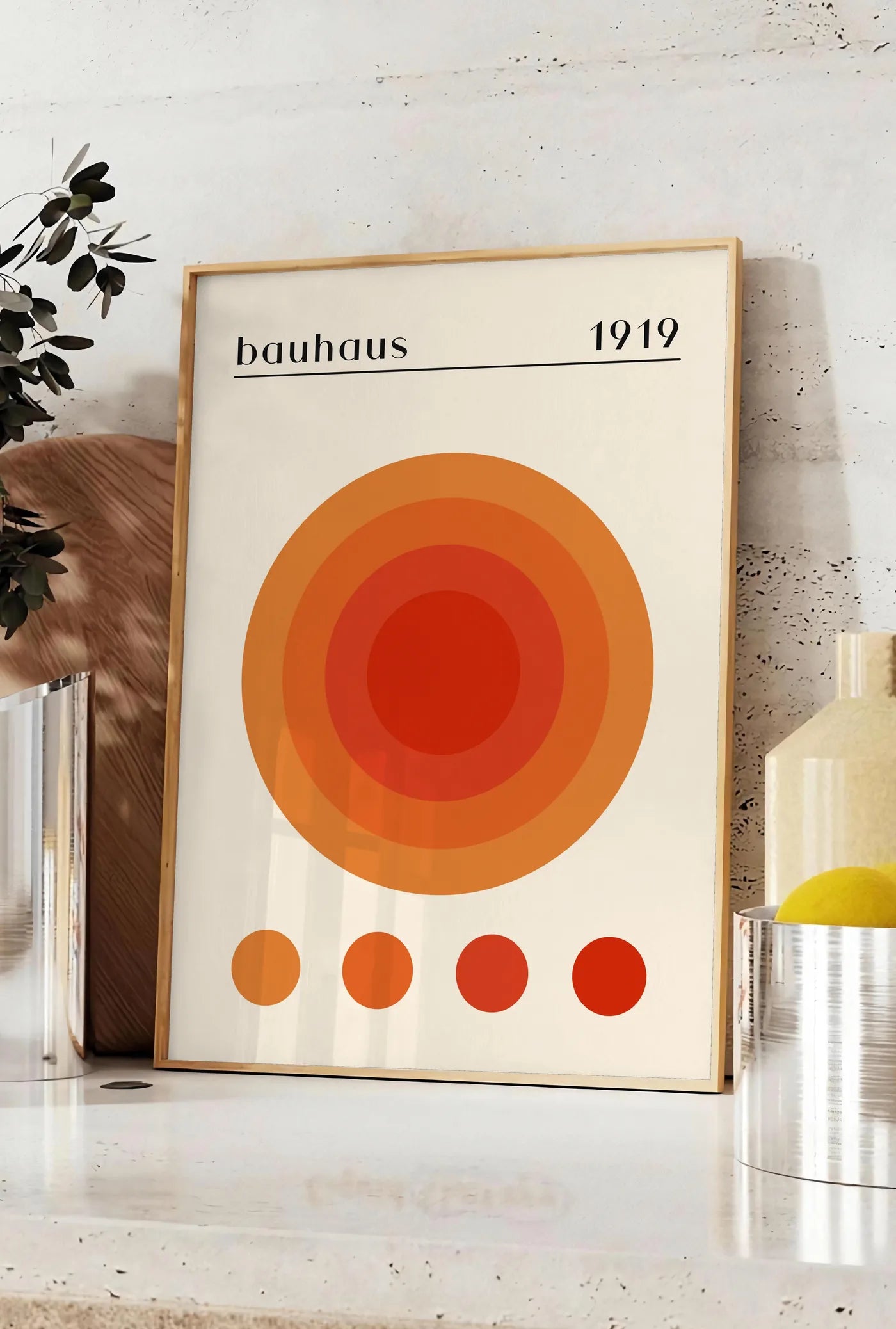 Affiche cercles Concentriques Chauds, posee sur un plan de travail de cuisine en pierre claire, entre une branche d'eucalyptus en vase et un bocal de citrons