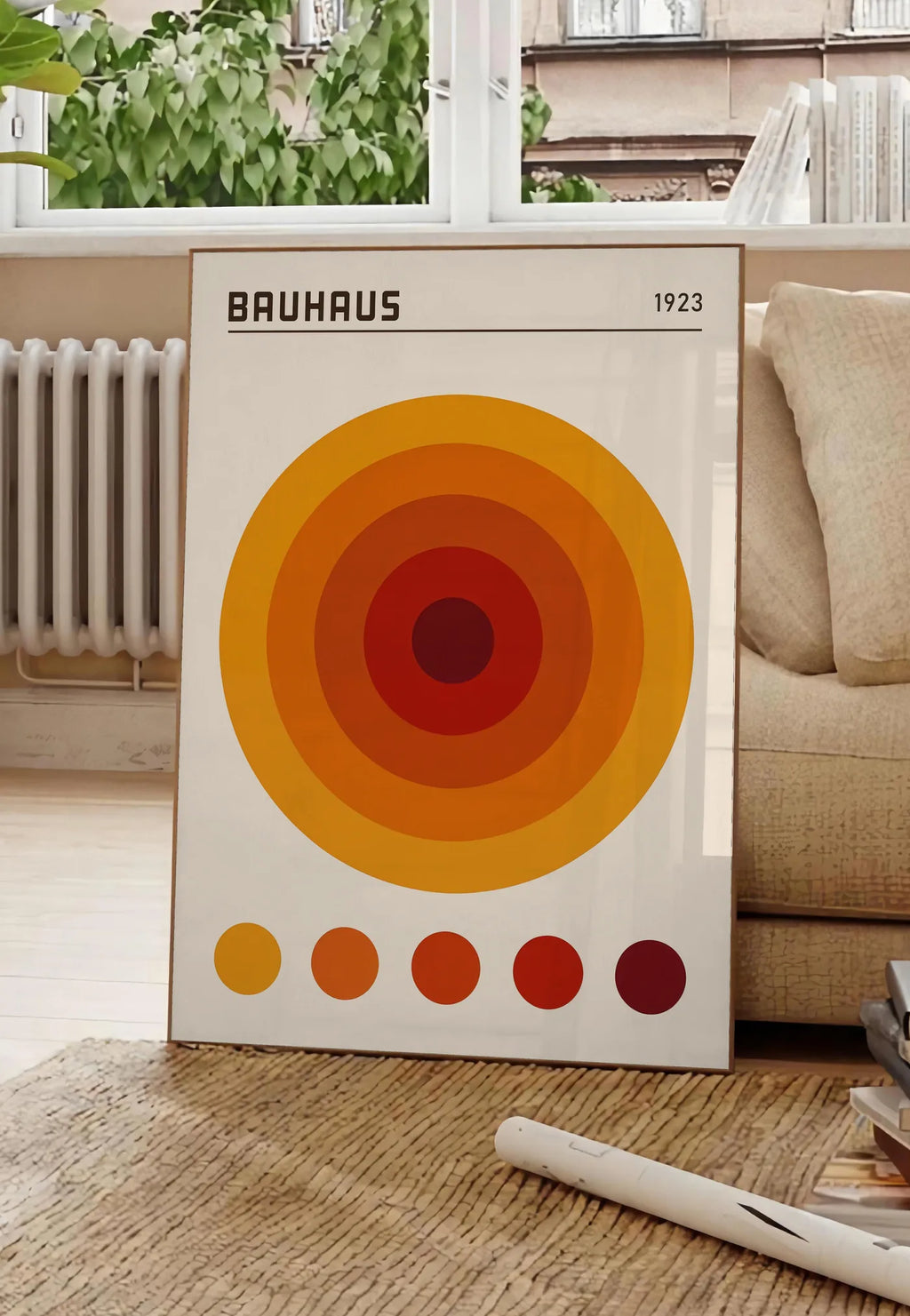 Poster cercles Concentriques Orange, posee au sol dans un salon parisien, devant une grande fenetre donnant sur un immeuble haussmannien, entre un ficus et un canape creme