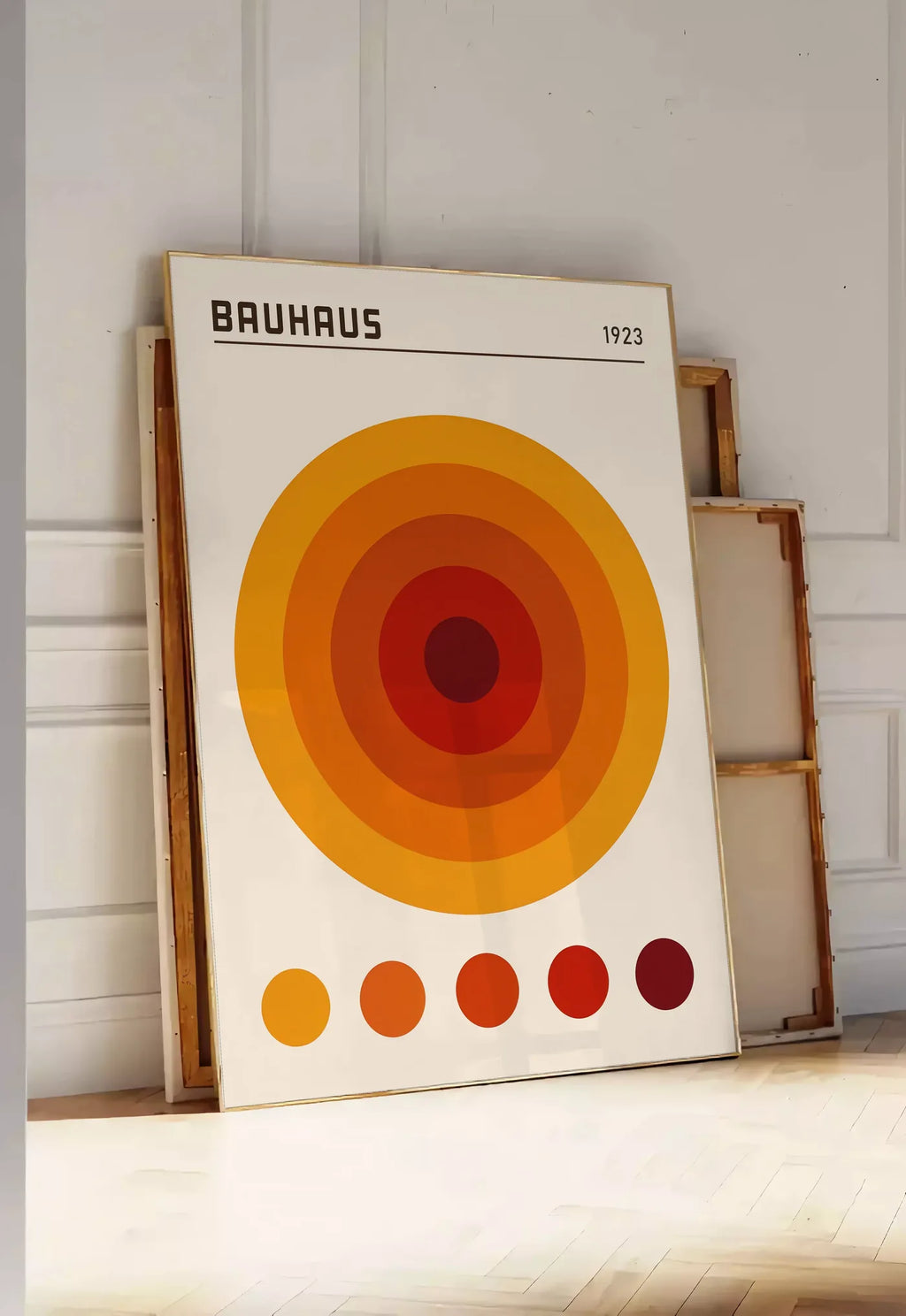 Tirage encadrable cercles Concentriques Orange, posee au sol dans une entree lumineuse, contre un mur a panneaux blancs, a cote de chassis en bois empiles