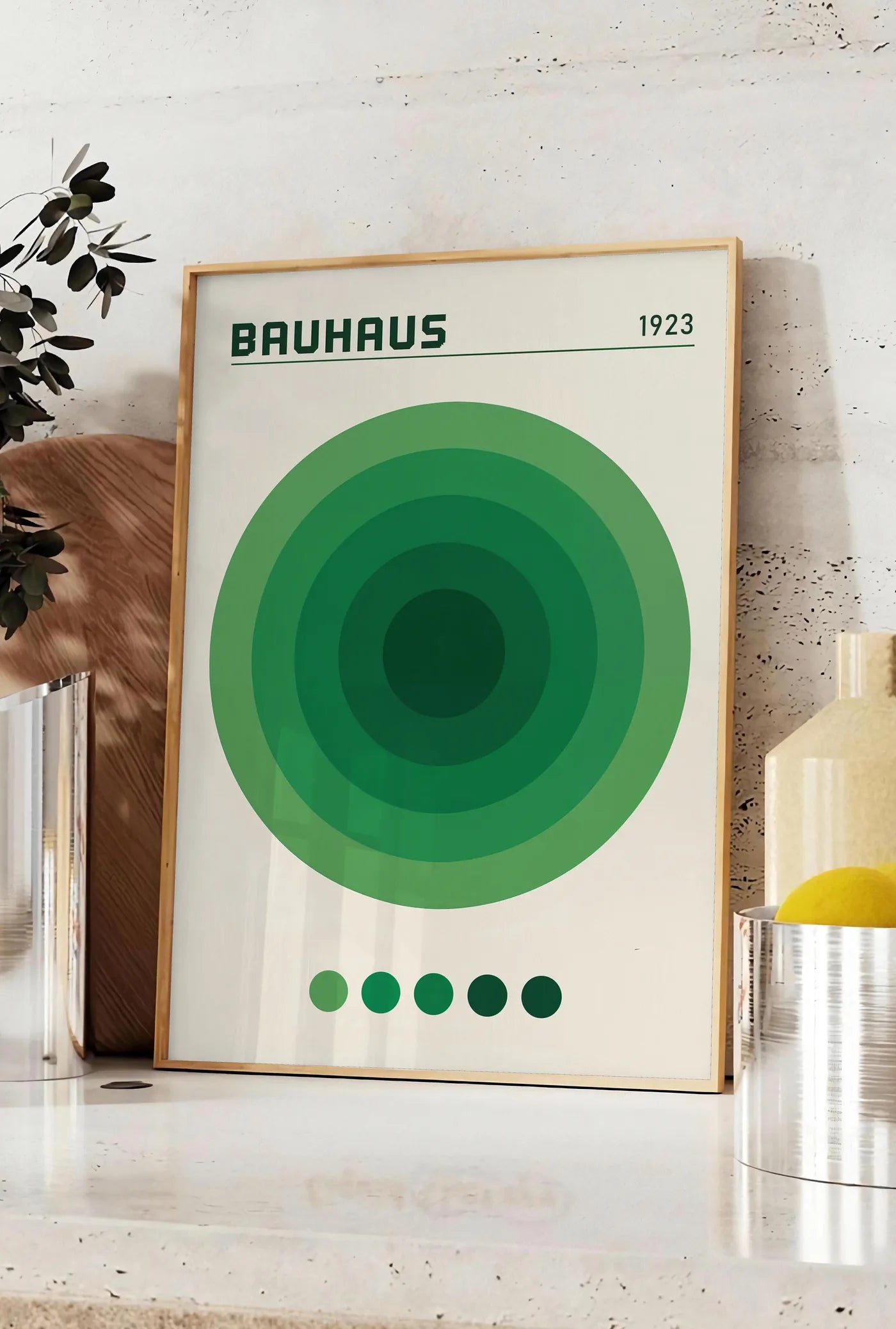 Affiche cercles Concentriques Verts, posee sur un plan de travail de cuisine en pierre claire, entre une branche d'eucalyptus en vase et un bocal de citrons