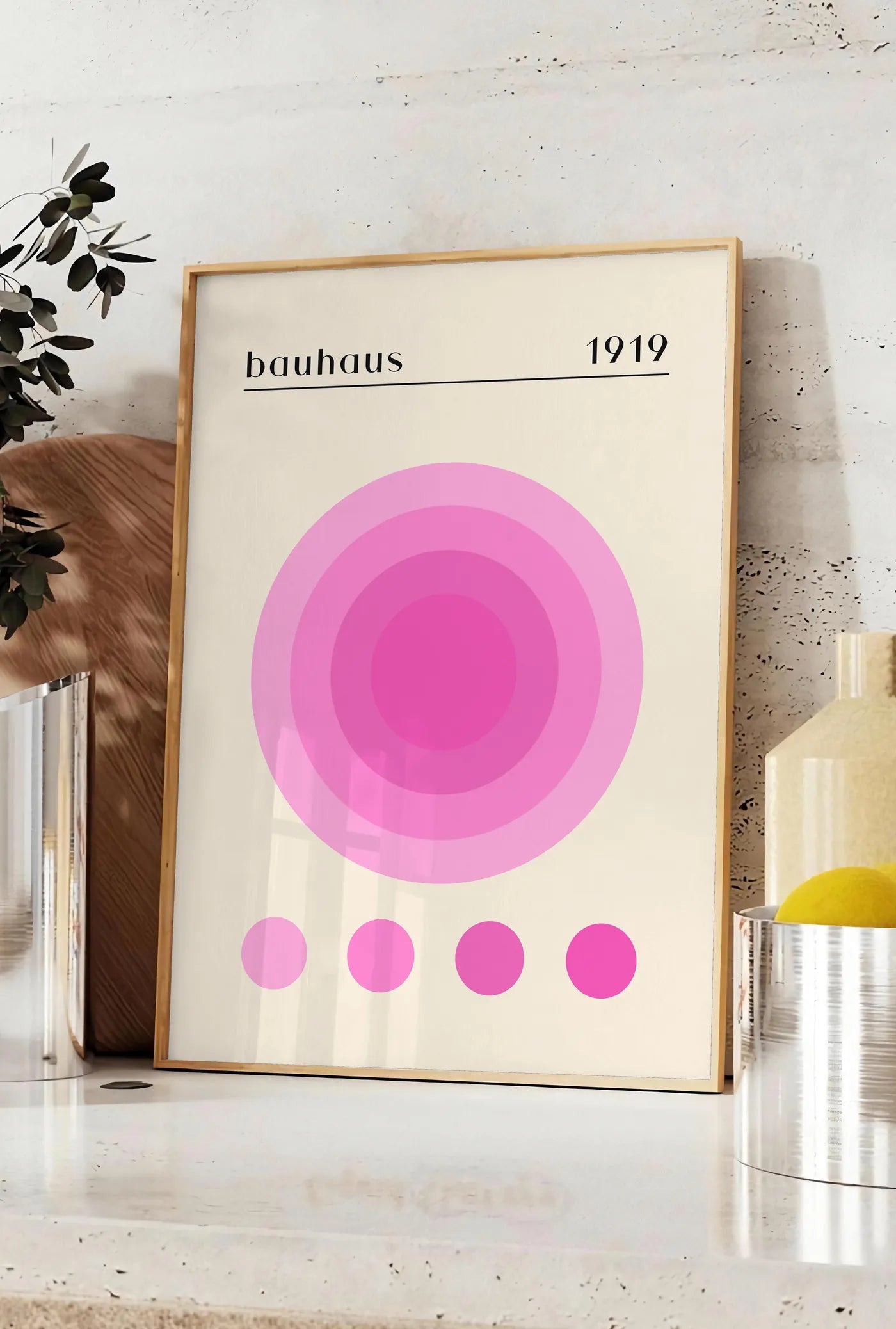 Affiche affiche Bauhaus 1919, posee sur un plan de travail de cuisine en pierre claire, entre une branche d'eucalyptus en vase et un bocal de citrons
