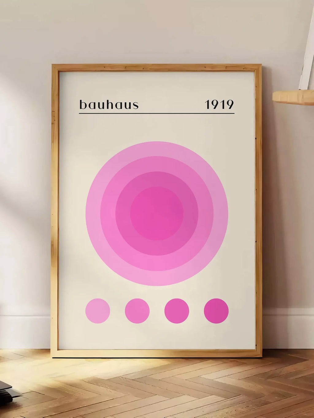 Estampe affiche Bauhaus 1919, posee au sol dans un coin salon, sur un parquet a chevrons, pres d'une table d'appoint en chene chargee de livres