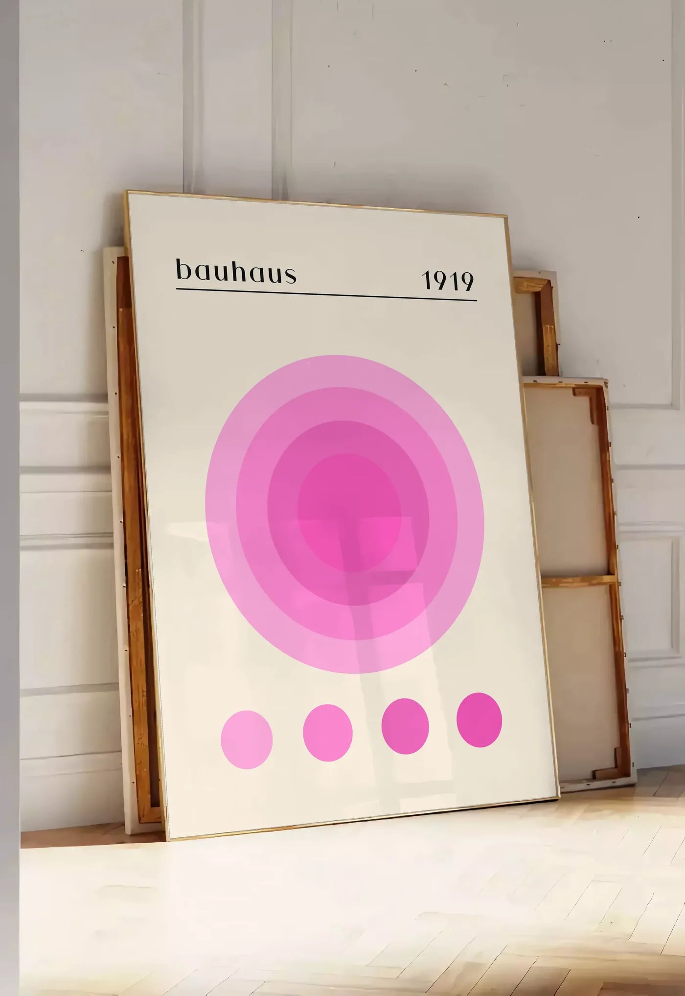 Tirage encadrable affiche Bauhaus 1919, posee au sol dans une entree lumineuse, contre un mur a panneaux blancs, a cote de chassis en bois empiles