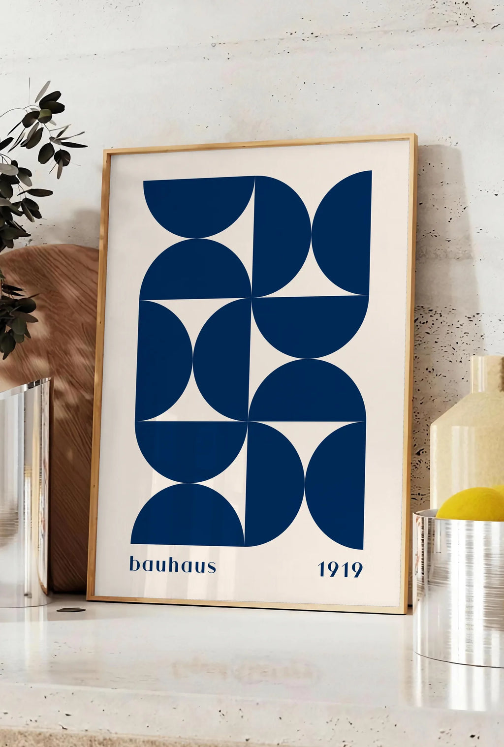 Affiche demi-Cercles Bleus, posee sur un plan de travail de cuisine en pierre claire, entre une branche d'eucalyptus en vase et un bocal de citrons