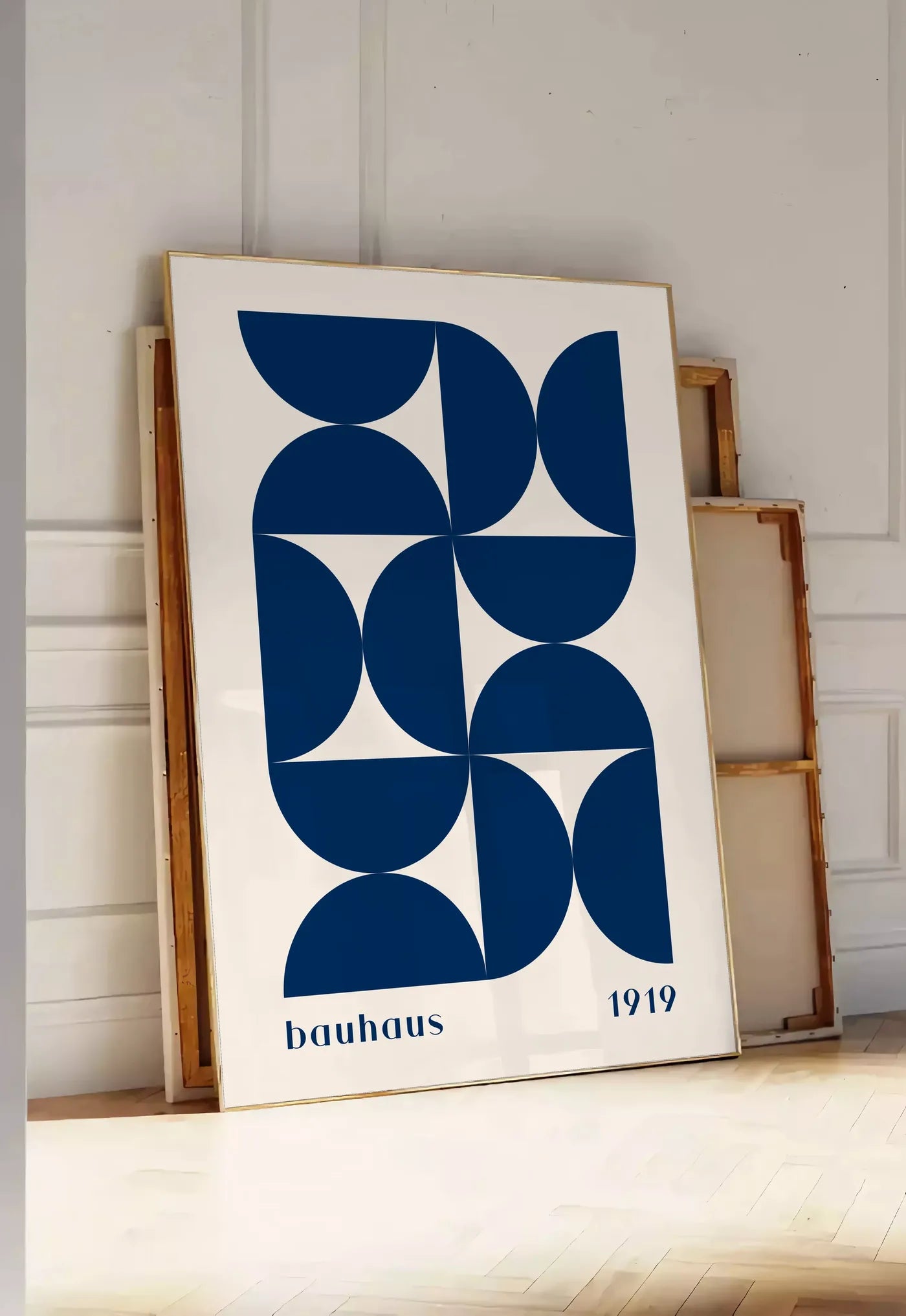 Tirage encadrable demi-Cercles Bleus, posee au sol dans une entree lumineuse, contre un mur a panneaux blancs, a cote de chassis en bois empiles