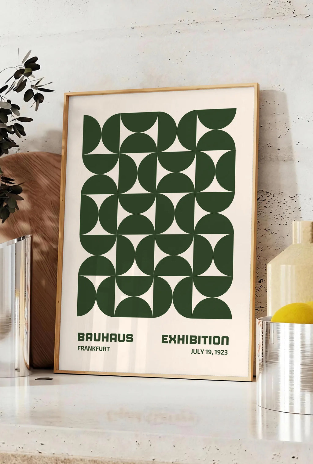 Affiche demi-Cercles Verts, posee sur un plan de travail de cuisine en pierre claire, entre une branche d'eucalyptus en vase et un bocal de citrons
