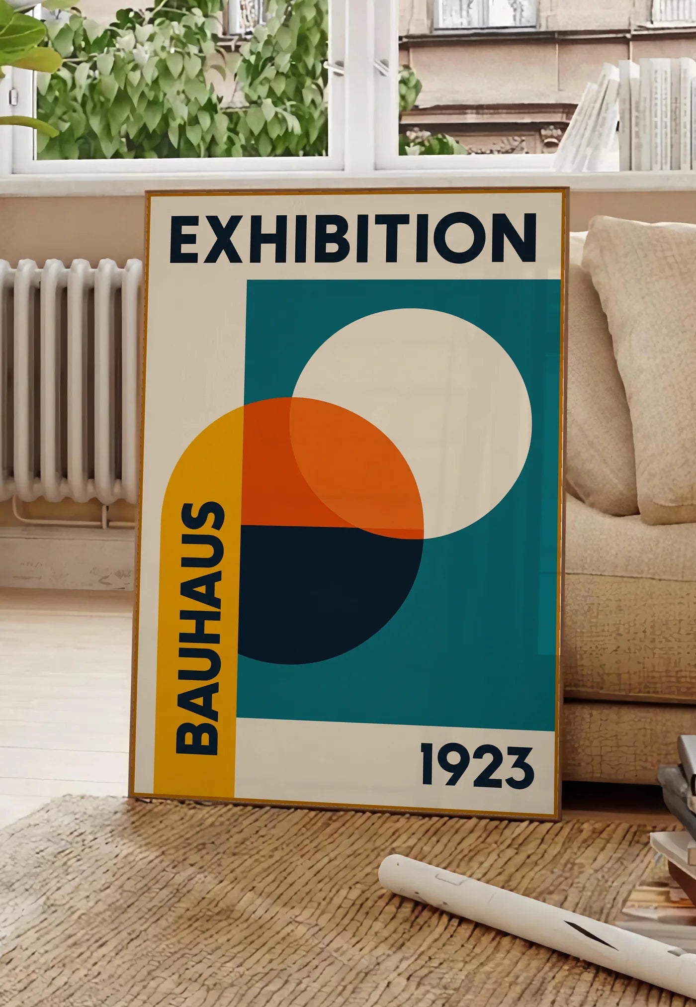 Poster cercles superposés ocre jaune et vermillon, posee au sol dans un salon parisien, devant une grande fenetre donnant sur un immeuble haussmannien, entre un ficus et un canape creme
