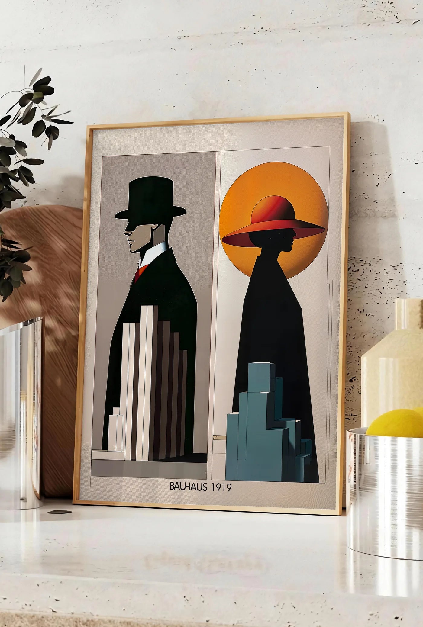Affiche figures Art Deco, posee sur un plan de travail de cuisine en pierre claire, entre une branche d'eucalyptus en vase et un bocal de citrons