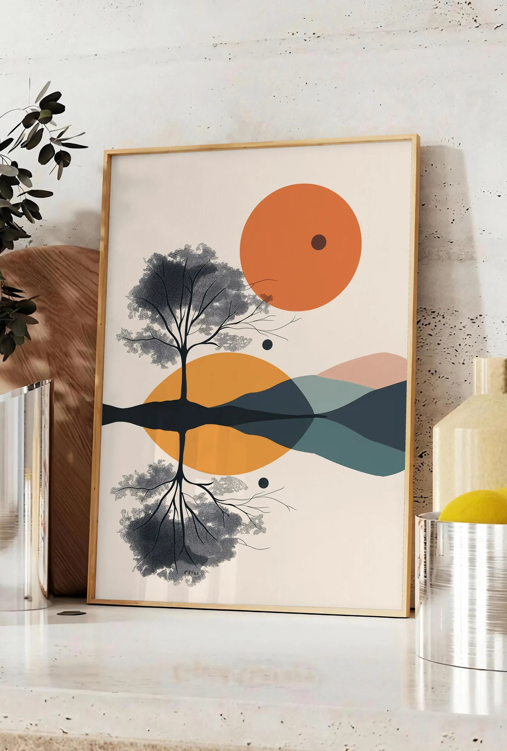 Affiche arbre stylisé noir avec feuillage pointilliste et cercles orange géométriques, posee sur un plan de travail de cuisine en pierre claire, entre une branche d'eucalyptus en vase et un bocal de citrons