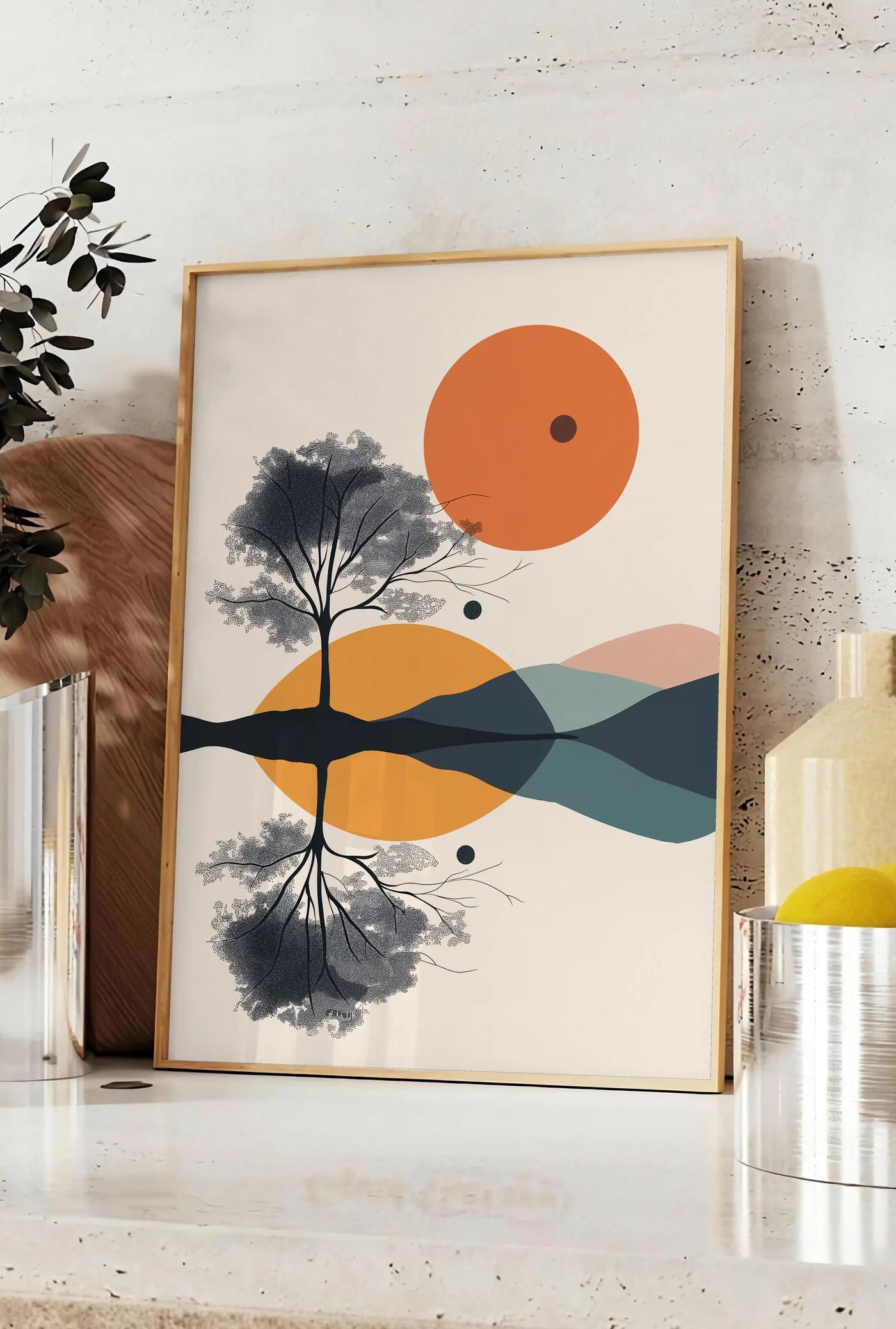 Affiche arbre stylisé noir avec feuillage pointilliste et cercles orange géométriques, posee sur un plan de travail de cuisine en pierre claire, entre une branche d'eucalyptus en vase et un bocal de citrons