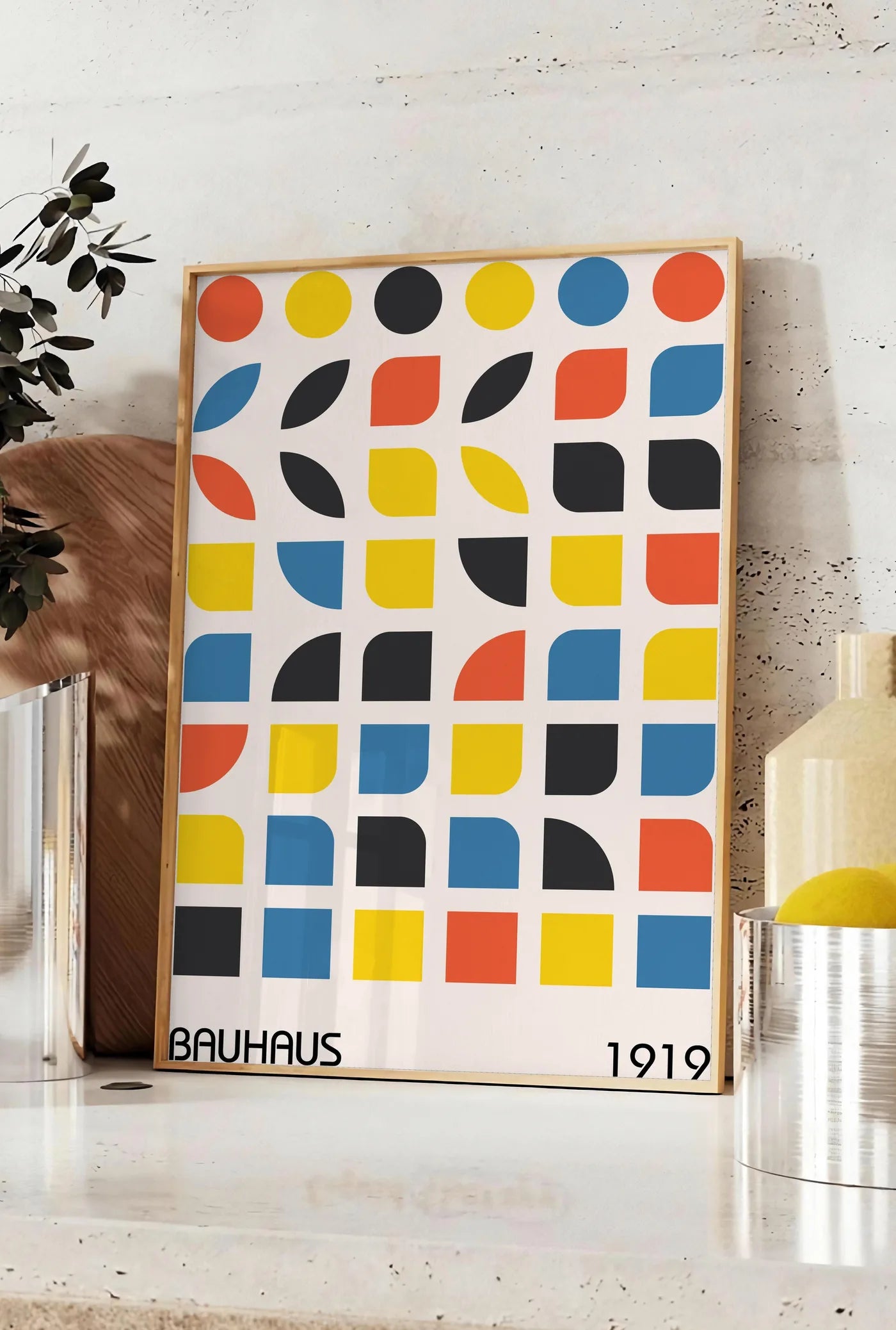 Affiche cercles et Carres, posee sur un plan de travail de cuisine en pierre claire, entre une branche d'eucalyptus en vase et un bocal de citrons