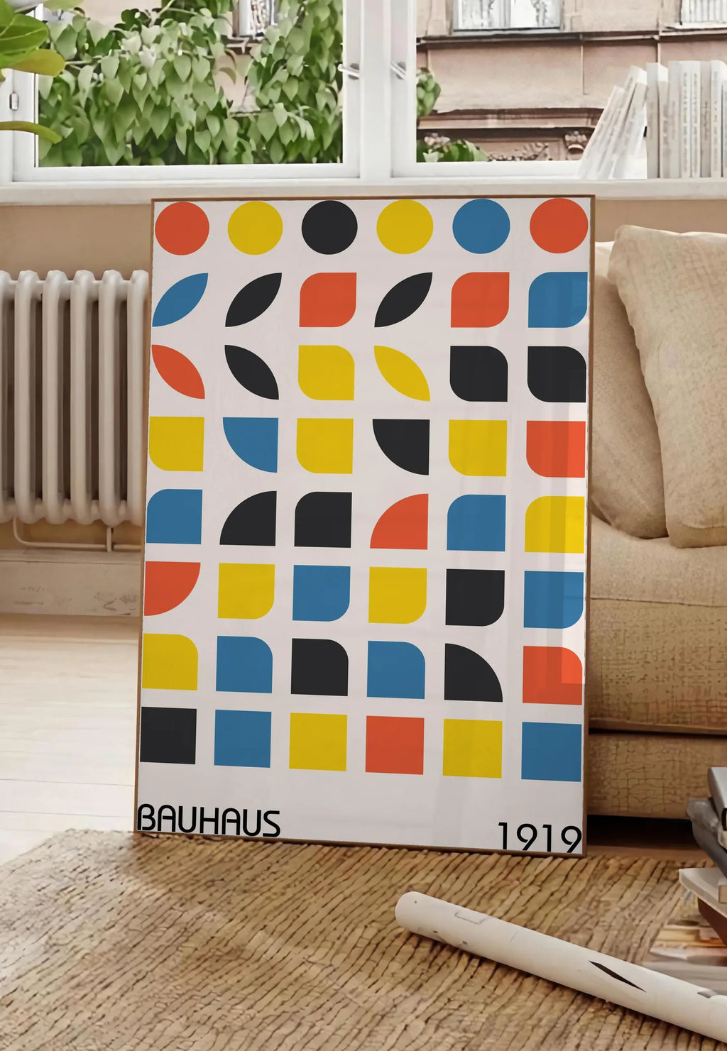 Poster cercles et Carres, posee au sol dans un salon parisien, devant une grande fenetre donnant sur un immeuble haussmannien, entre un ficus et un canape creme