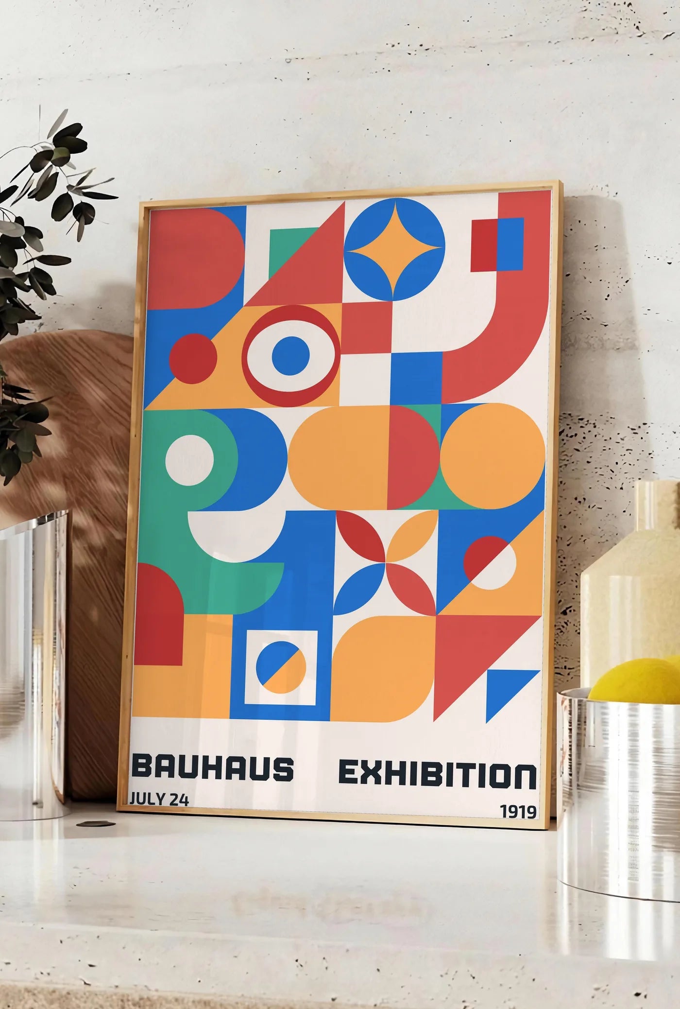 Affiche grille de Formes Colorees, posee sur un plan de travail de cuisine en pierre claire, entre une branche d'eucalyptus en vase et un bocal de citrons