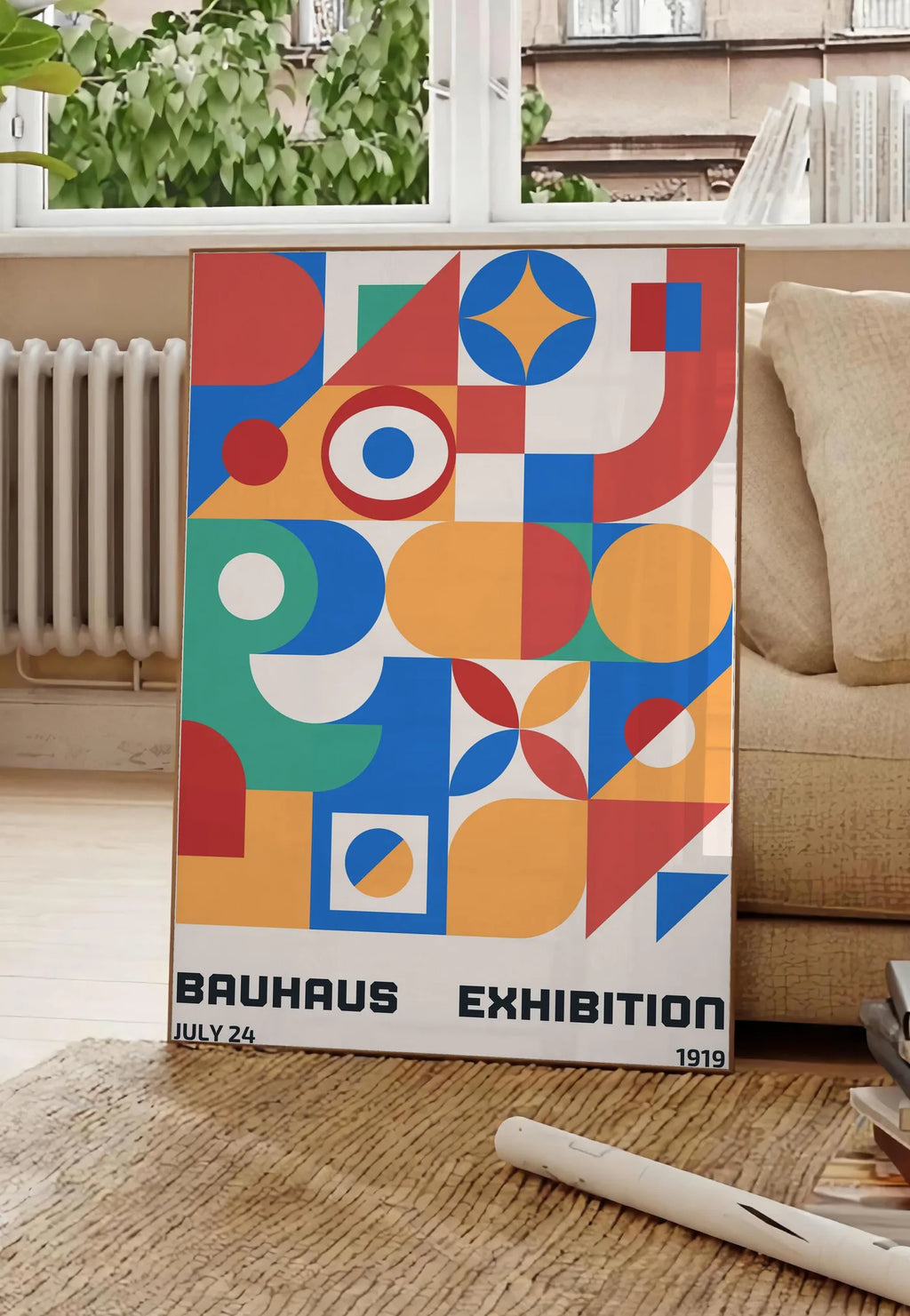 Poster grille de Formes Colorees, posee au sol dans un salon parisien, devant une grande fenetre donnant sur un immeuble haussmannien, entre un ficus et un canape creme