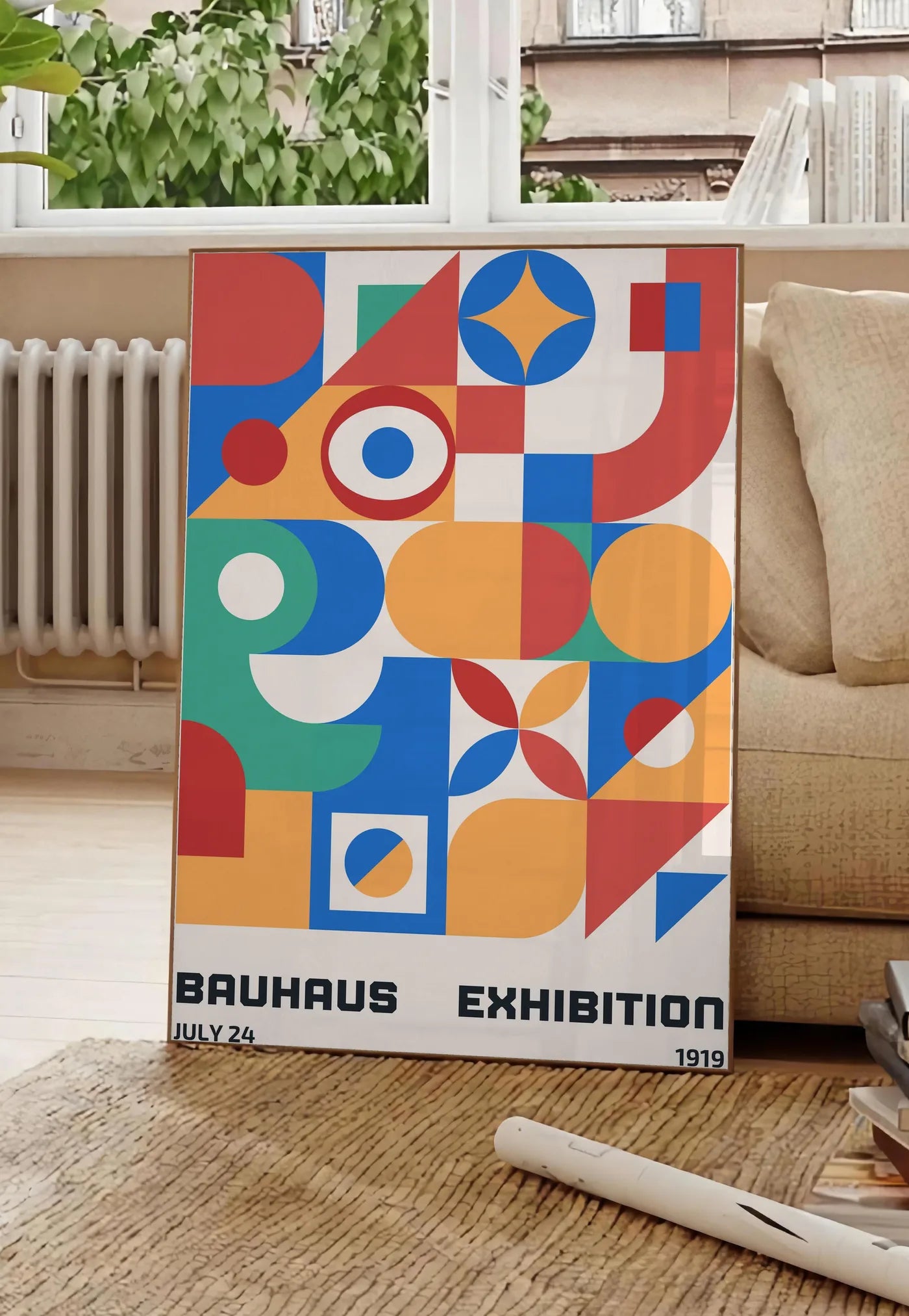 Poster grille de Formes Colorees, posee au sol dans un salon parisien, devant une grande fenetre donnant sur un immeuble haussmannien, entre un ficus et un canape creme