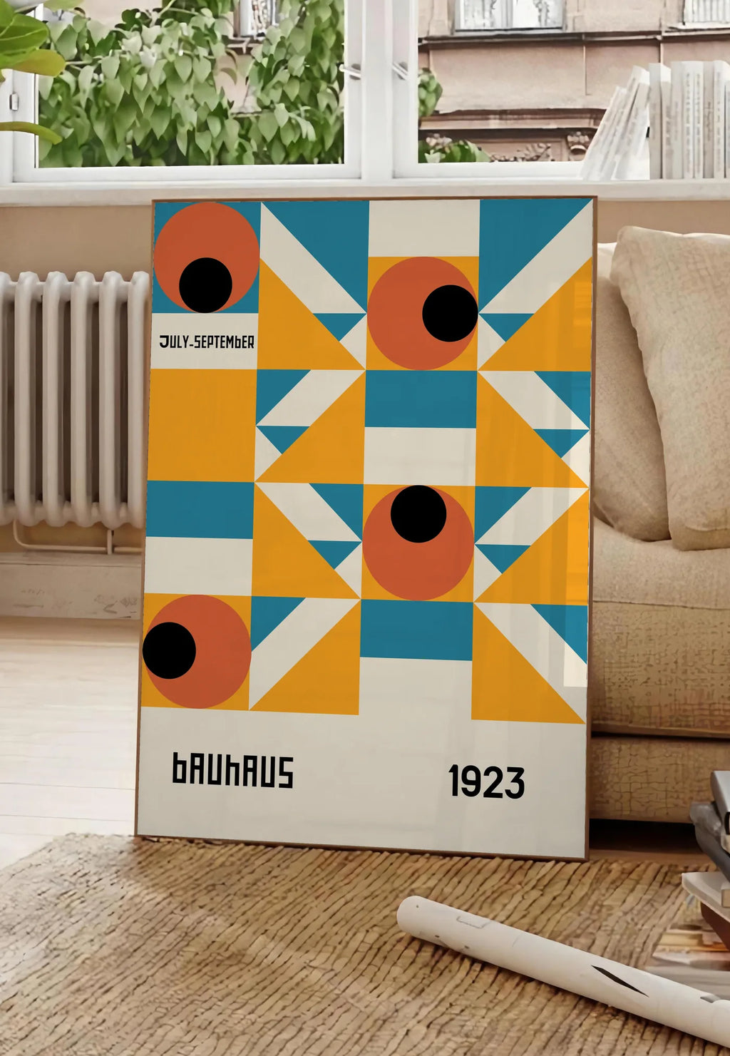 Poster grille aux Yeux Orange, posee au sol dans un salon parisien, devant une grande fenetre donnant sur un immeuble haussmannien, entre un ficus et un canape creme