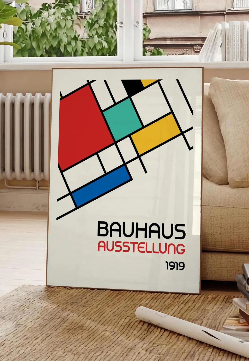 Poster blocs Mondrian, posee au sol dans un salon parisien, devant une grande fenetre donnant sur un immeuble haussmannien, entre un ficus et un canape creme