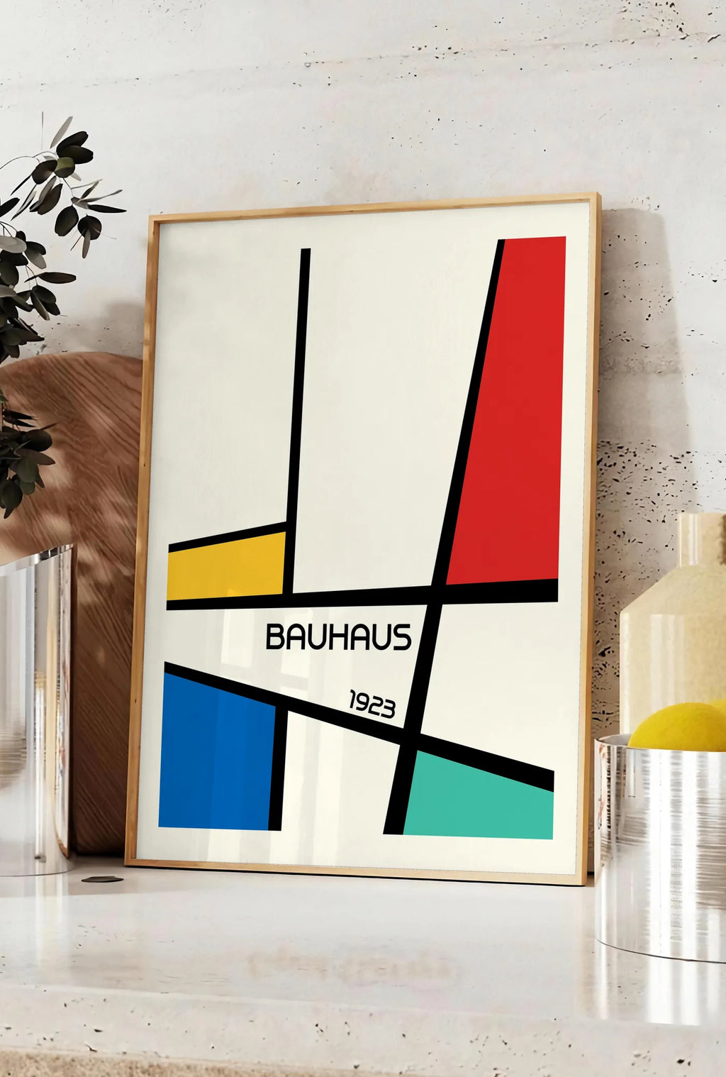 Affiche mondrian Diagonal, posee sur un plan de travail de cuisine en pierre claire, entre une branche d'eucalyptus en vase et un bocal de citrons