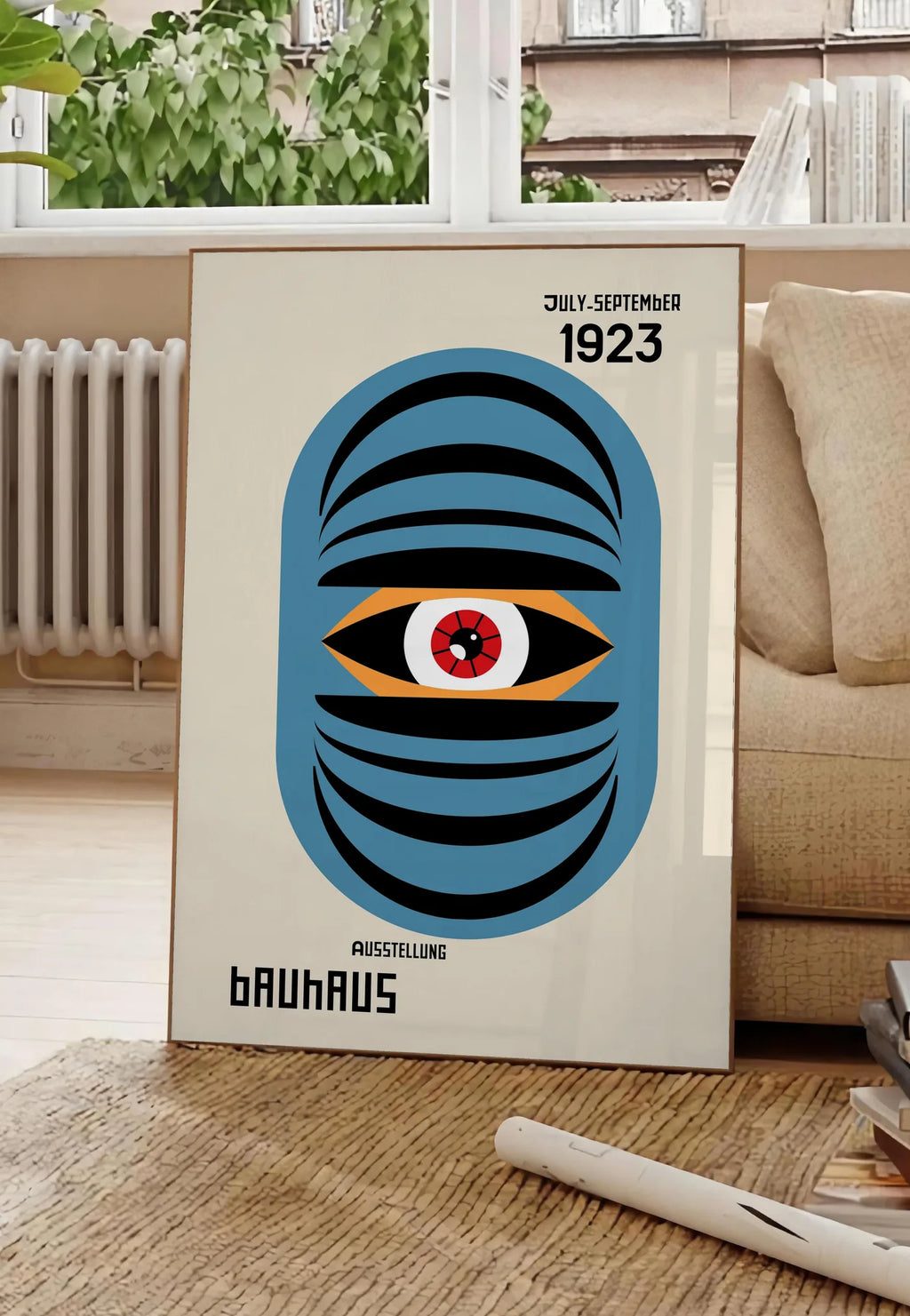 Poster oeil Bleu Surreel, posee au sol dans un salon parisien, devant une grande fenetre donnant sur un immeuble haussmannien, entre un ficus et un canape creme