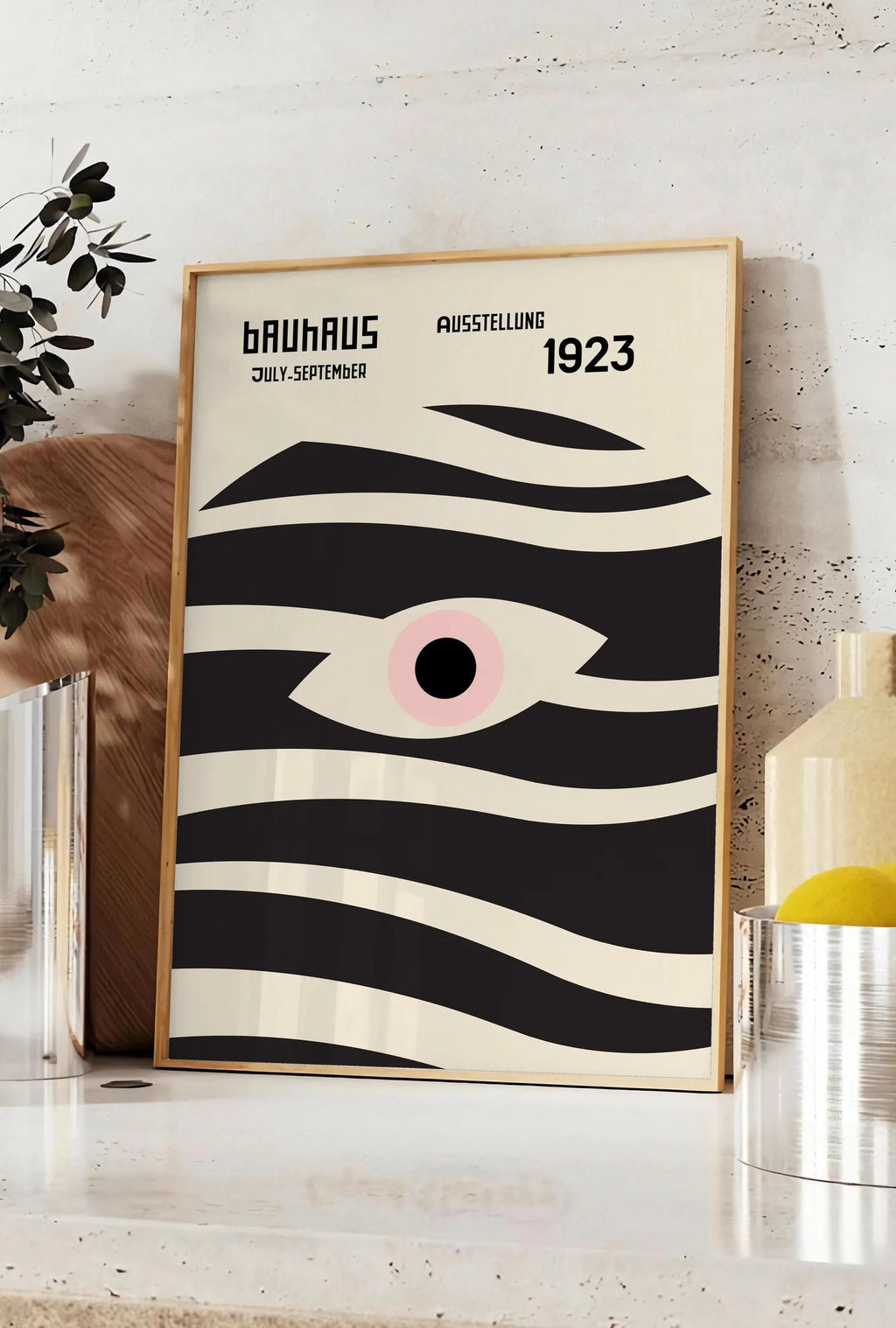 Affiche oeil et Vagues, posee sur un plan de travail de cuisine en pierre claire, entre une branche d'eucalyptus en vase et un bocal de citrons