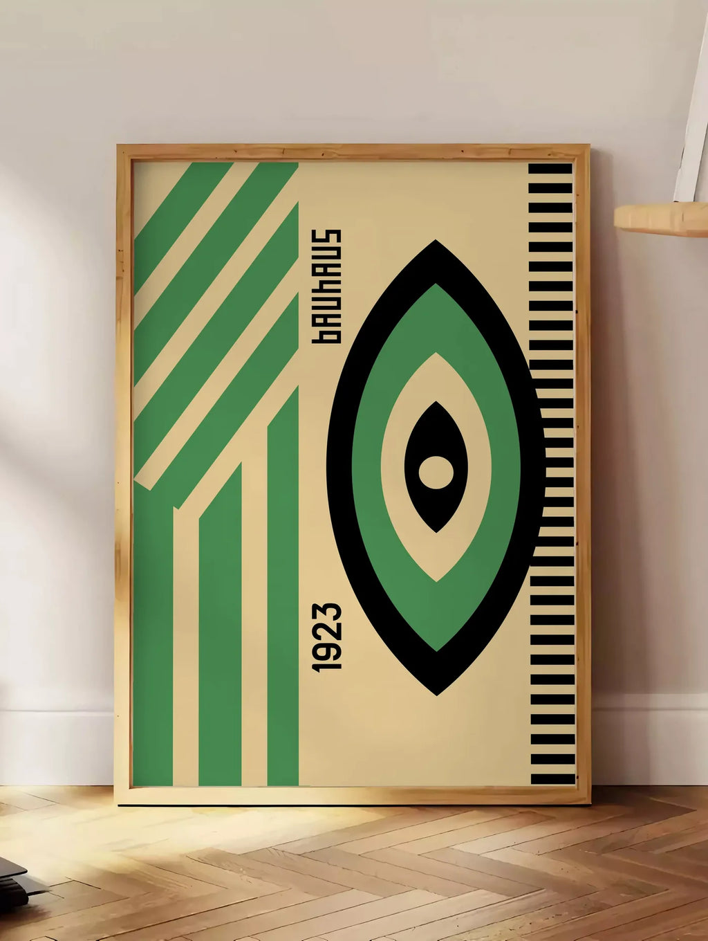 Estampe oeil Vert et Noir, posee au sol dans un coin salon, sur un parquet a chevrons, pres d'une table d'appoint en chene chargee de livres
