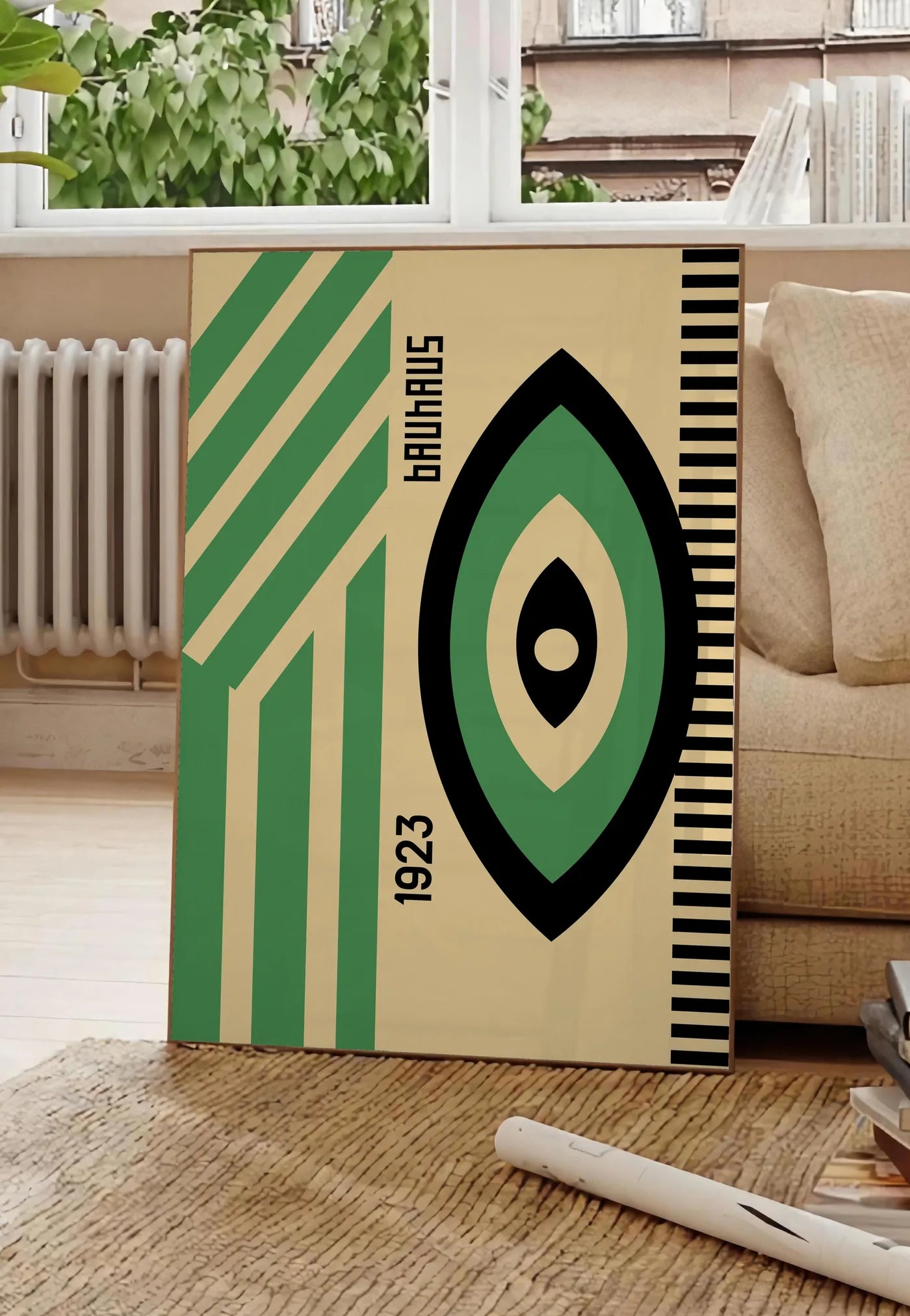 Poster oeil Vert et Noir, posee au sol dans un salon parisien, devant une grande fenetre donnant sur un immeuble haussmannien, entre un ficus et un canape creme