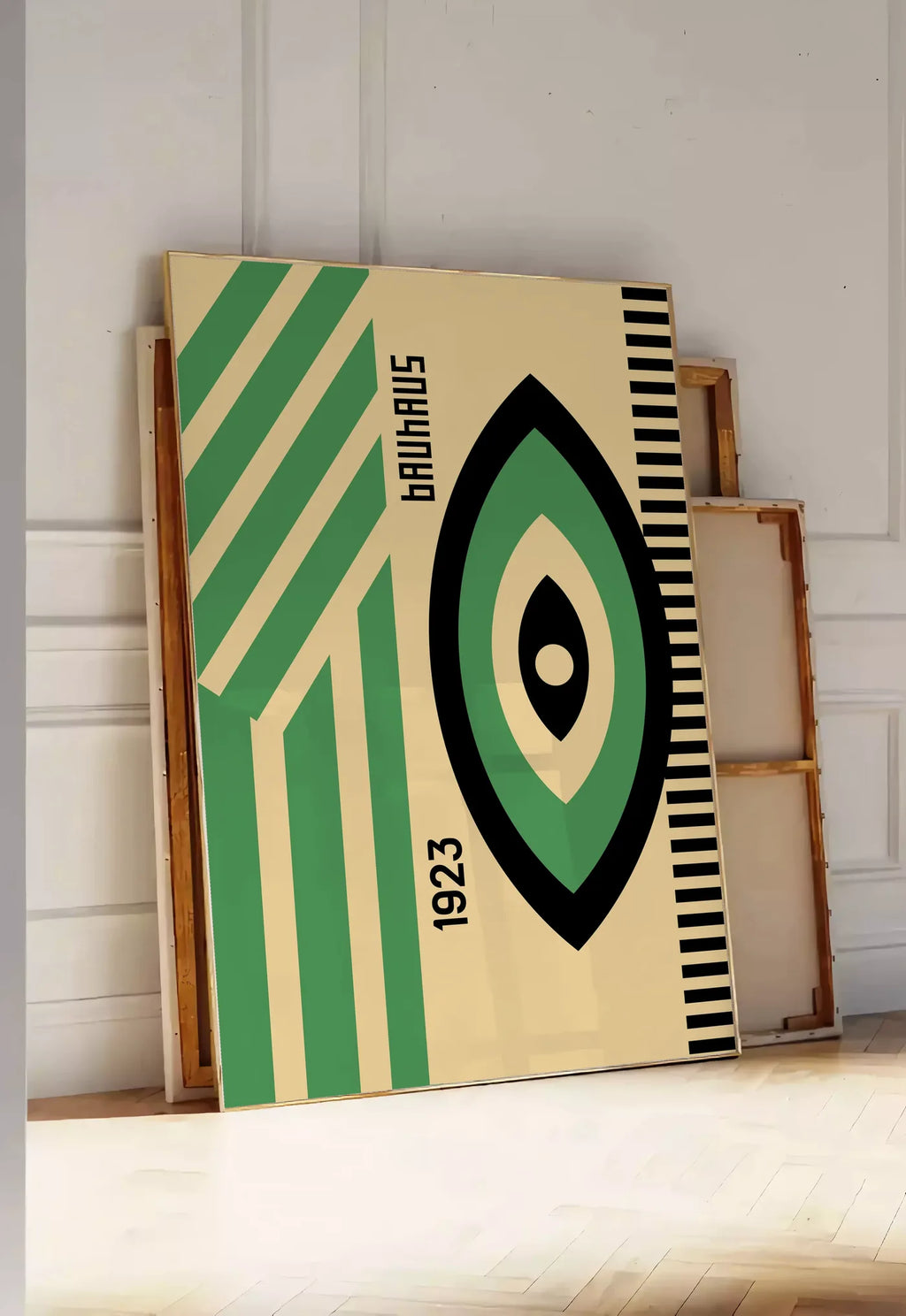 Tirage encadrable oeil Vert et Noir, posee au sol dans une entree lumineuse, contre un mur a panneaux blancs, a cote de chassis en bois empiles