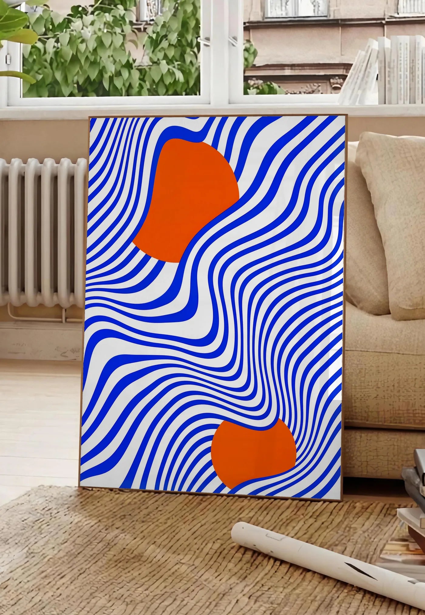 Poster op Art Bleu et Orange, posee au sol dans un salon parisien, devant une grande fenetre donnant sur un immeuble haussmannien, entre un ficus et un canape creme