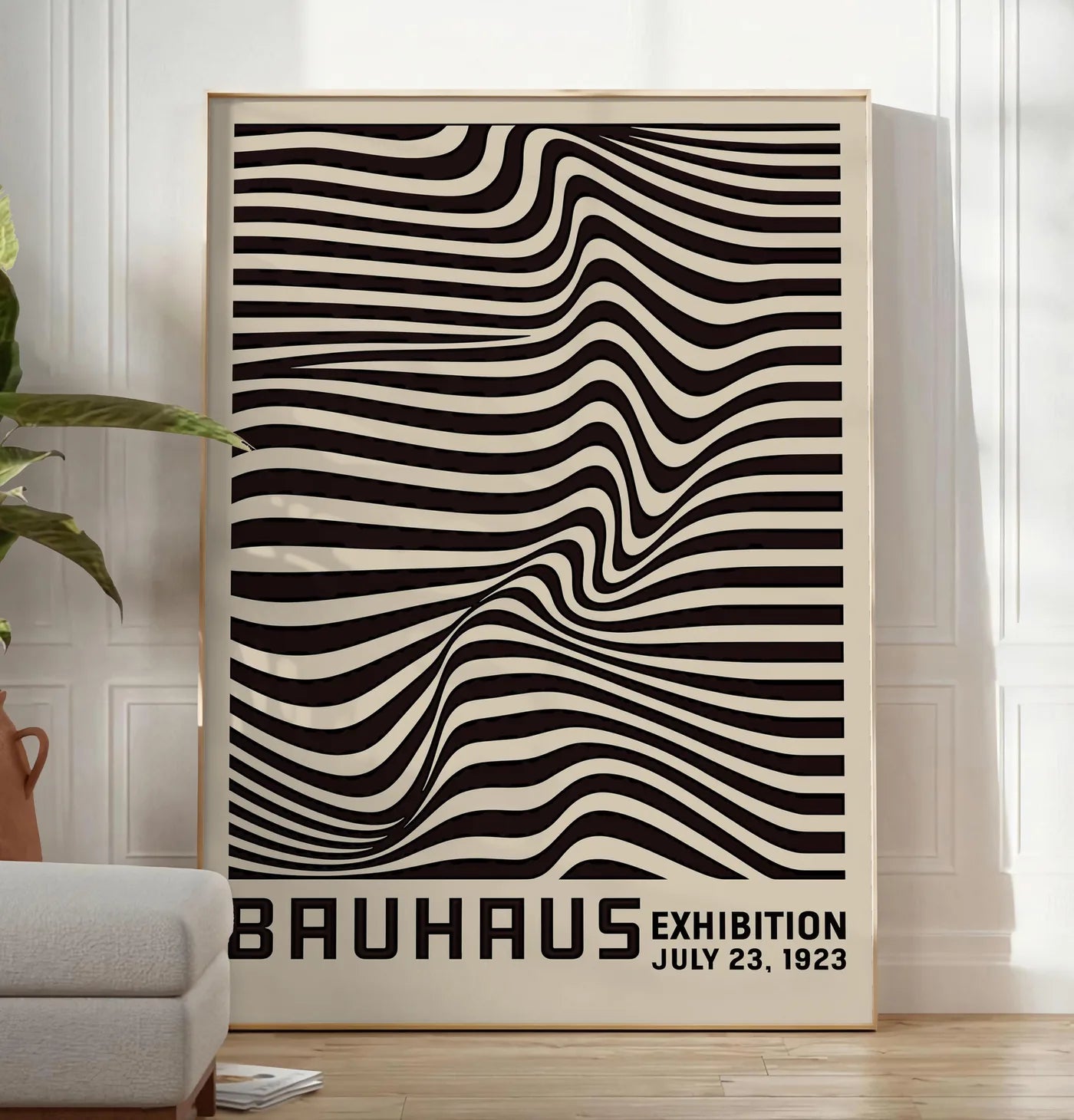 Reproduction op Art Vagues Noires, posee au sol dans un salon minimaliste clair, a cote d'un canape beige et d'une plante verte, sur un parquet clair