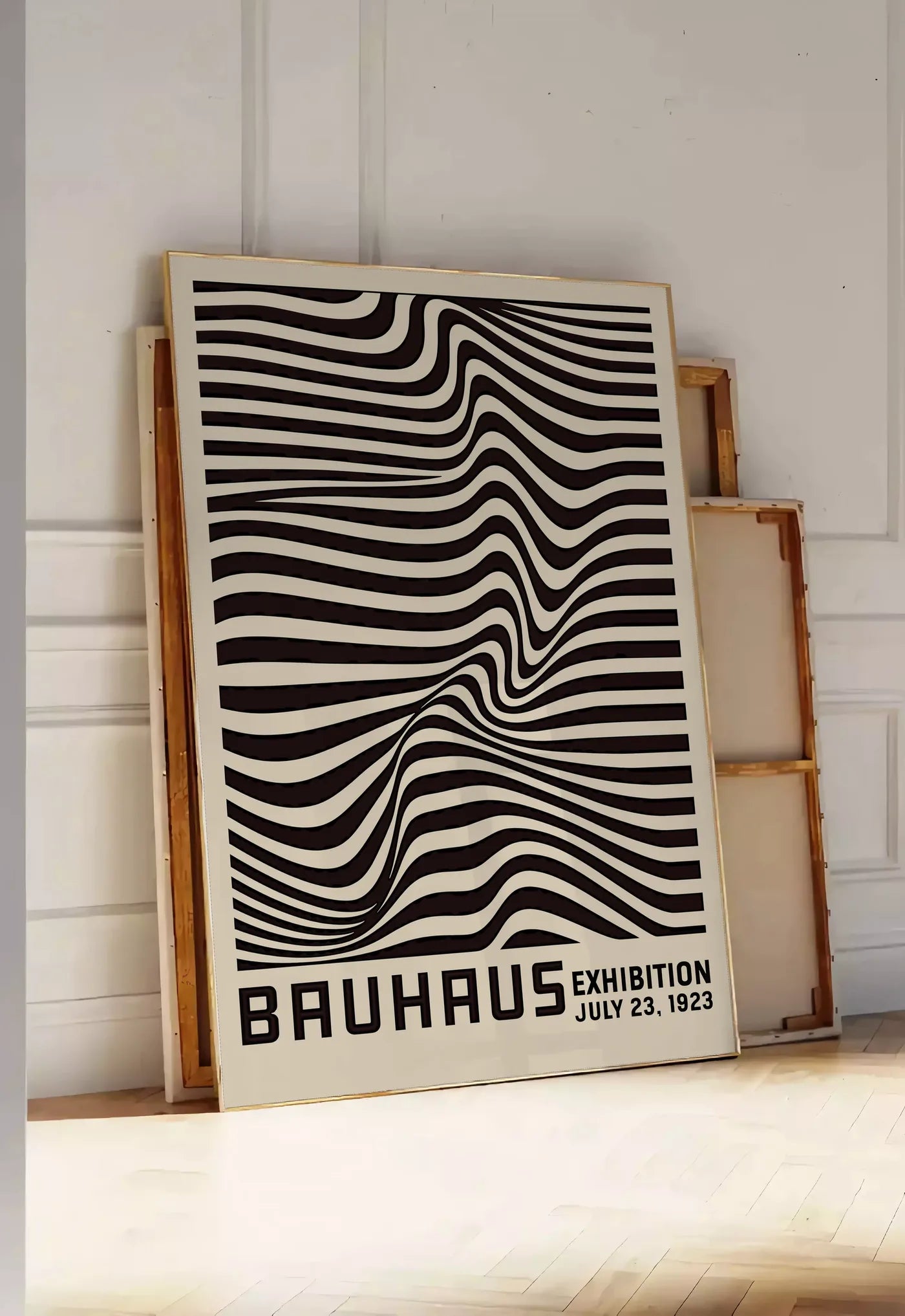 Tirage encadrable op Art Vagues Noires, posee au sol dans une entree lumineuse, contre un mur a panneaux blancs, a cote de chassis en bois empiles