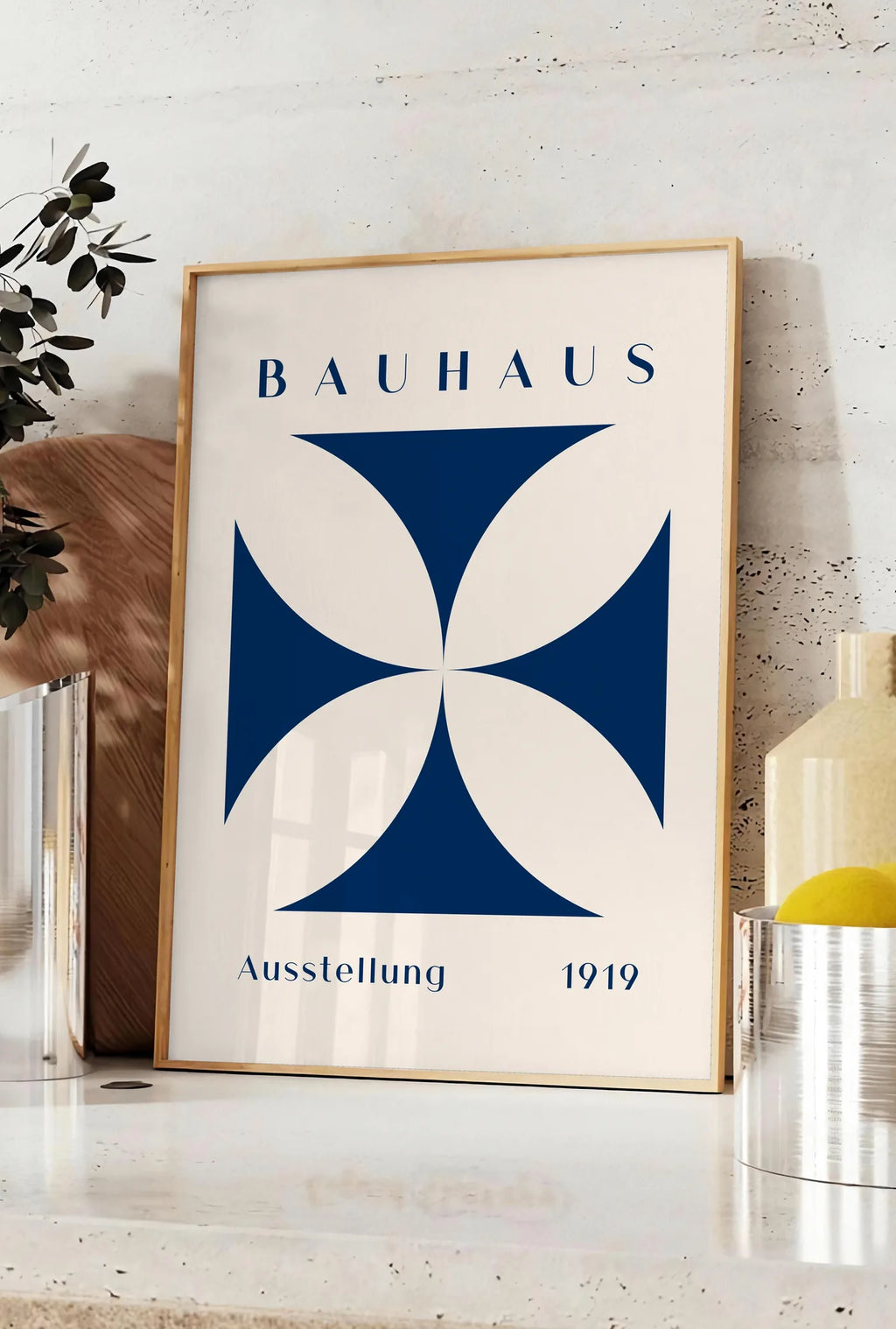 Affiche quatre-Petales Bleus, posee sur un plan de travail de cuisine en pierre claire, entre une branche d'eucalyptus en vase et un bocal de citrons