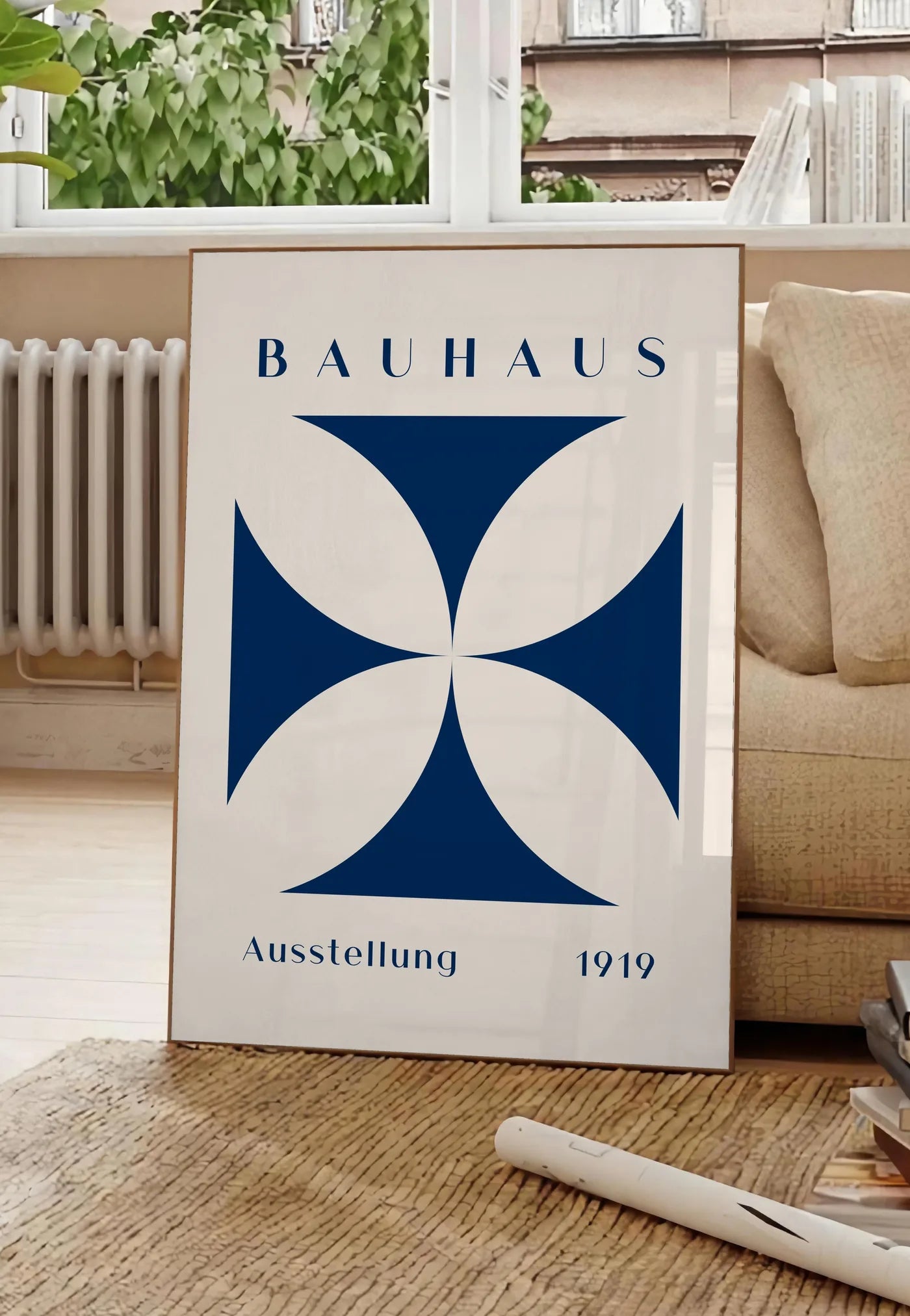 Poster quatre-Petales Bleus, posee au sol dans un salon parisien, devant une grande fenetre donnant sur un immeuble haussmannien, entre un ficus et un canape creme