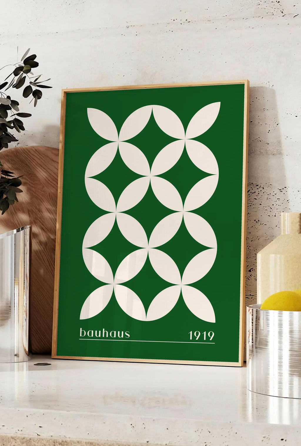 Affiche quatre-Petales Verts, posee sur un plan de travail de cuisine en pierre claire, entre une branche d'eucalyptus en vase et un bocal de citrons