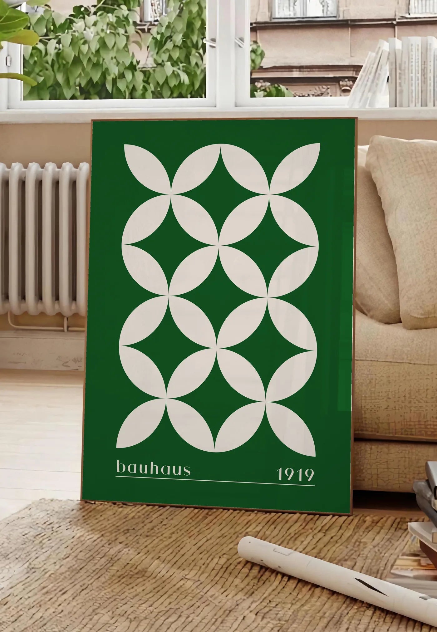 Poster quatre-Petales Verts, posee au sol dans un salon parisien, devant une grande fenetre donnant sur un immeuble haussmannien, entre un ficus et un canape creme