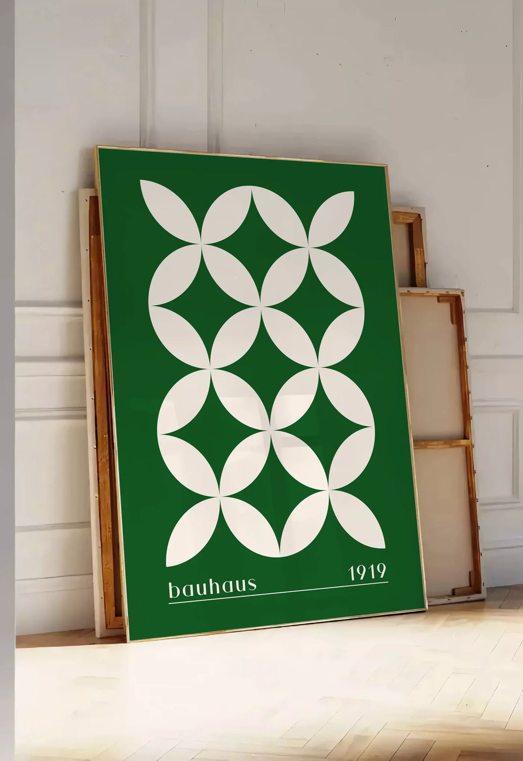 Tirage encadrable quatre-Petales Verts, posee au sol dans une entree lumineuse, contre un mur a panneaux blancs, a cote de chassis en bois empiles