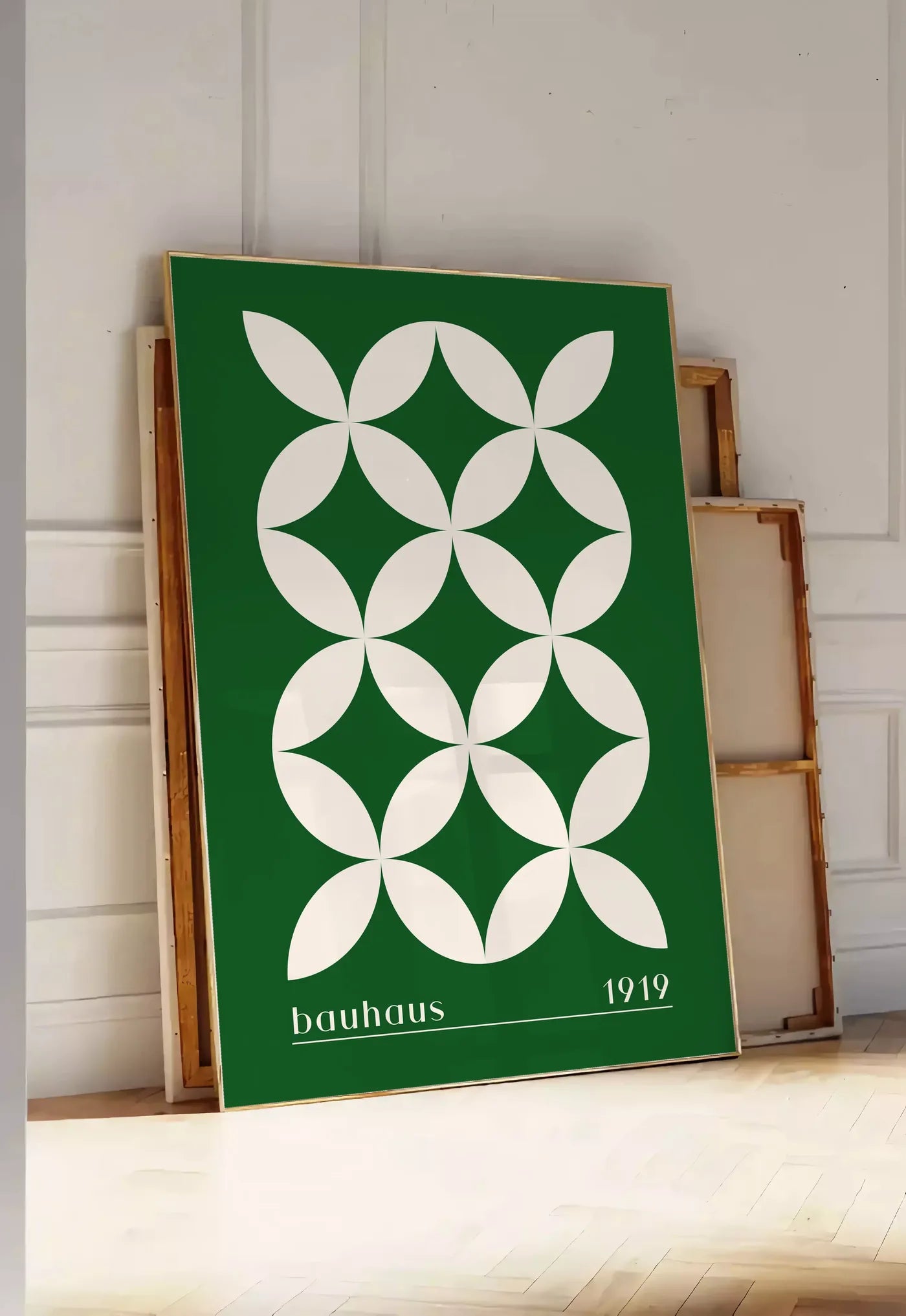 Tirage encadrable quatre-Petales Verts, posee au sol dans une entree lumineuse, contre un mur a panneaux blancs, a cote de chassis en bois empiles