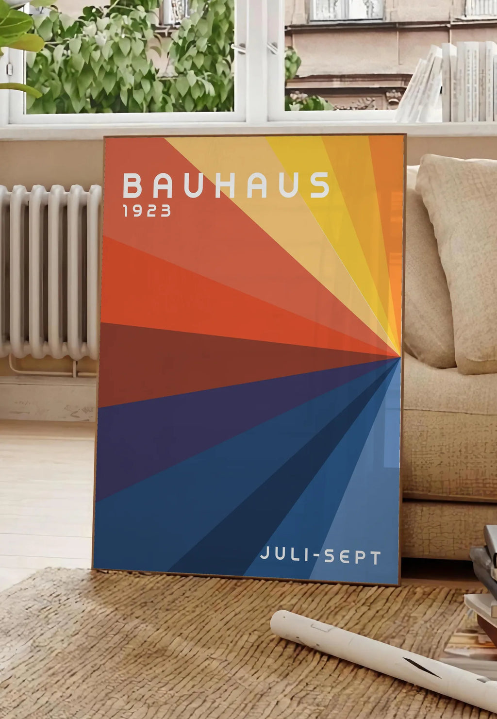 Poster roue de Couleurs, posee au sol dans un salon parisien, devant une grande fenetre donnant sur un immeuble haussmannien, entre un ficus et un canape creme