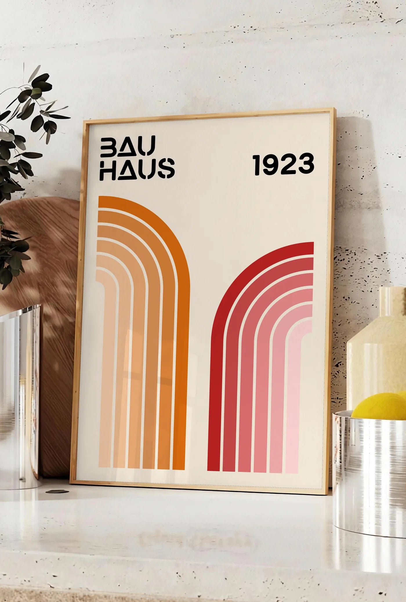Affiche rubans Courbes, posee sur un plan de travail de cuisine en pierre claire, entre une branche d'eucalyptus en vase et un bocal de citrons